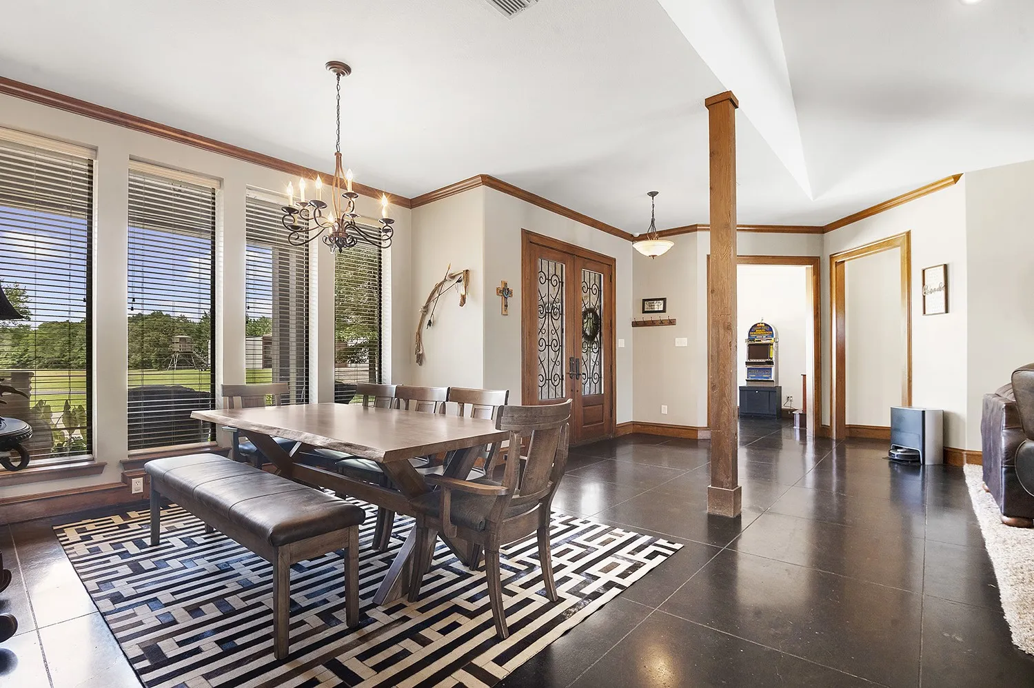 Dining area with multiple tall windows, dark flooring, and a decorative chandelier