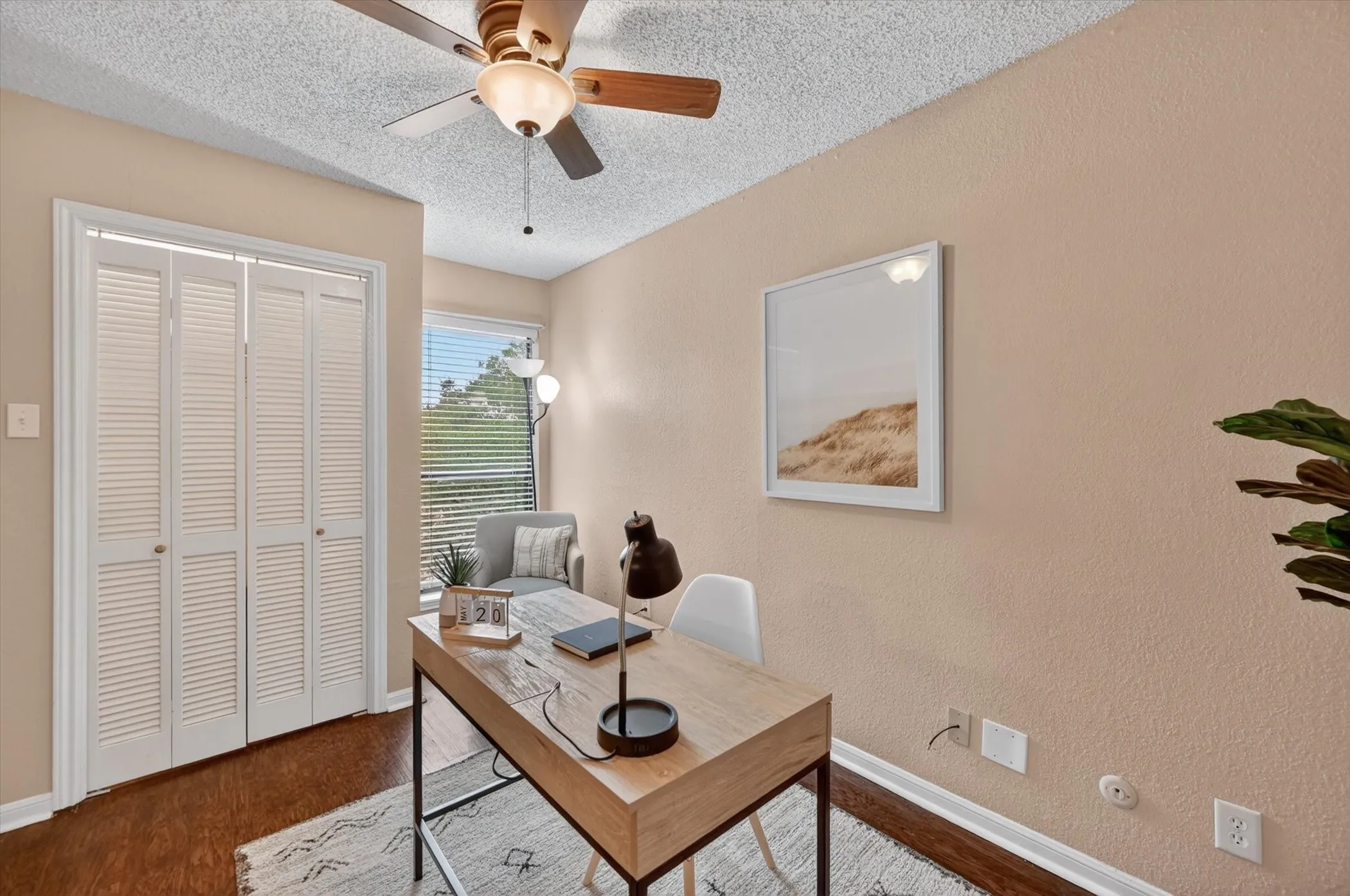 Room featuring wood-finish flooring, a ceiling fan with integrated lighting, and a window with horizontal blinds