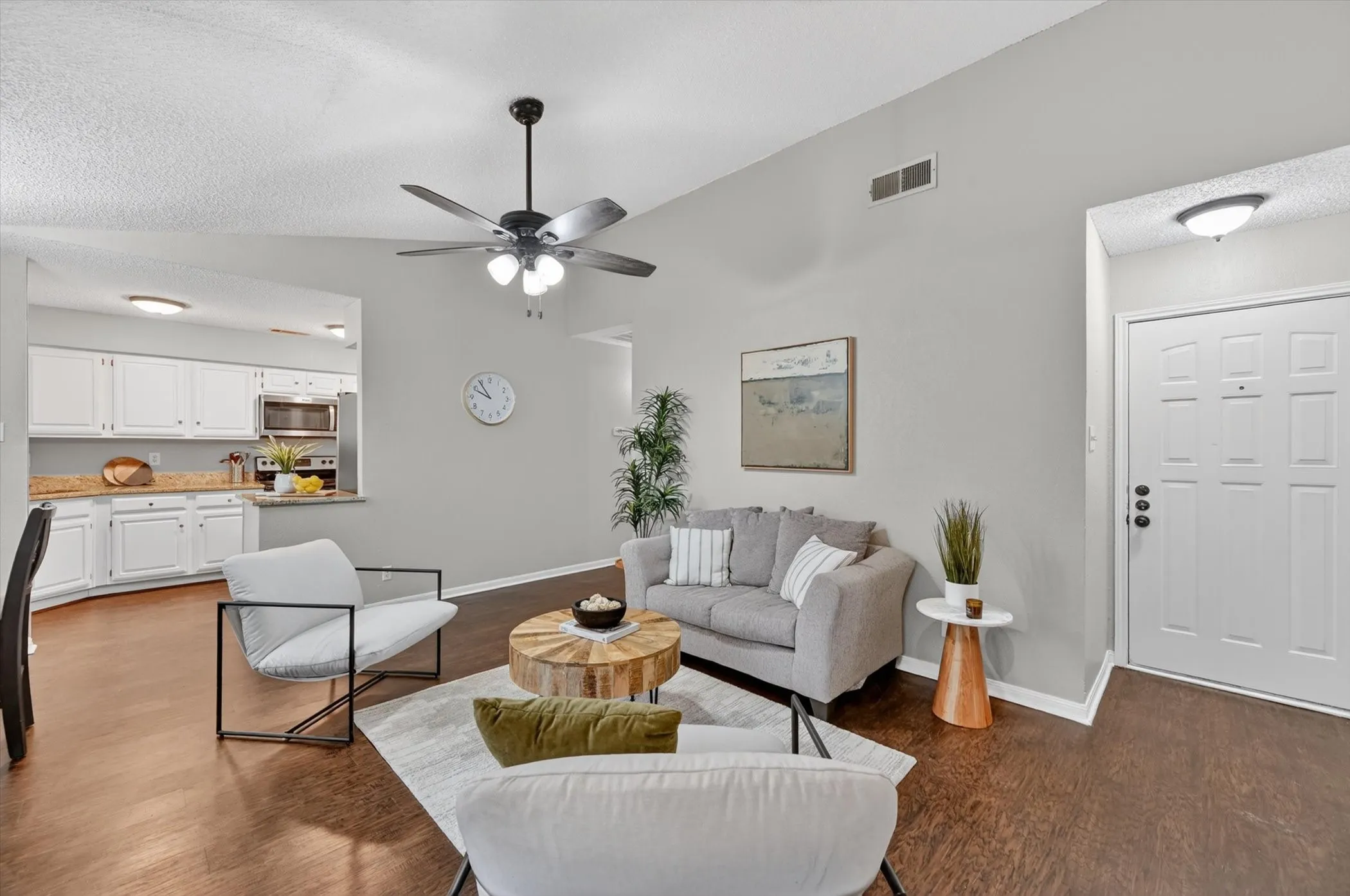 Living area featuring vaulted ceilings, wood-finish flooring, and a ceiling fan