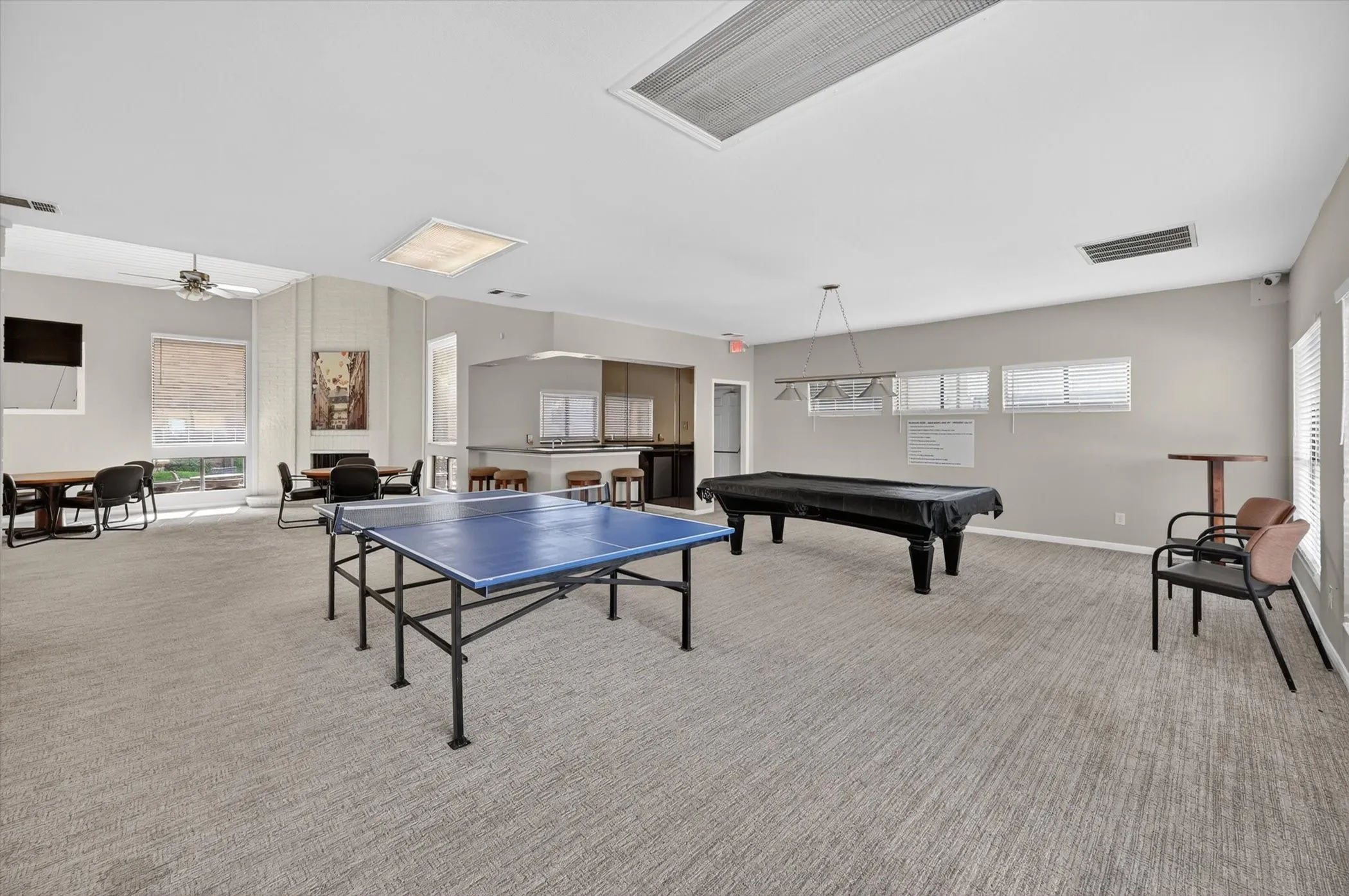 Spacious common area featuring neutral-toned carpeting, a built-in bar, recessed lighting, and multiple windows with blinds