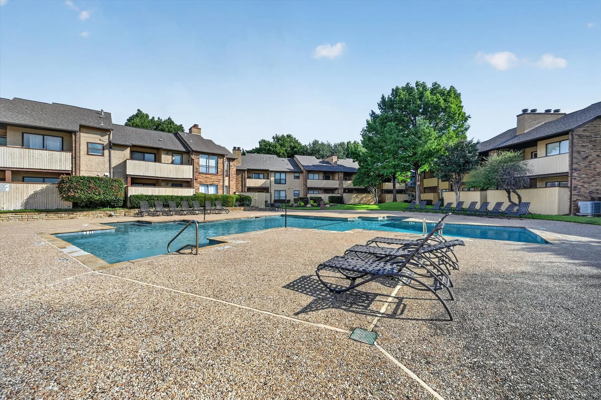 Expansive pool area featuring two distinct swimming pools and a surrounding aggregate concrete deck