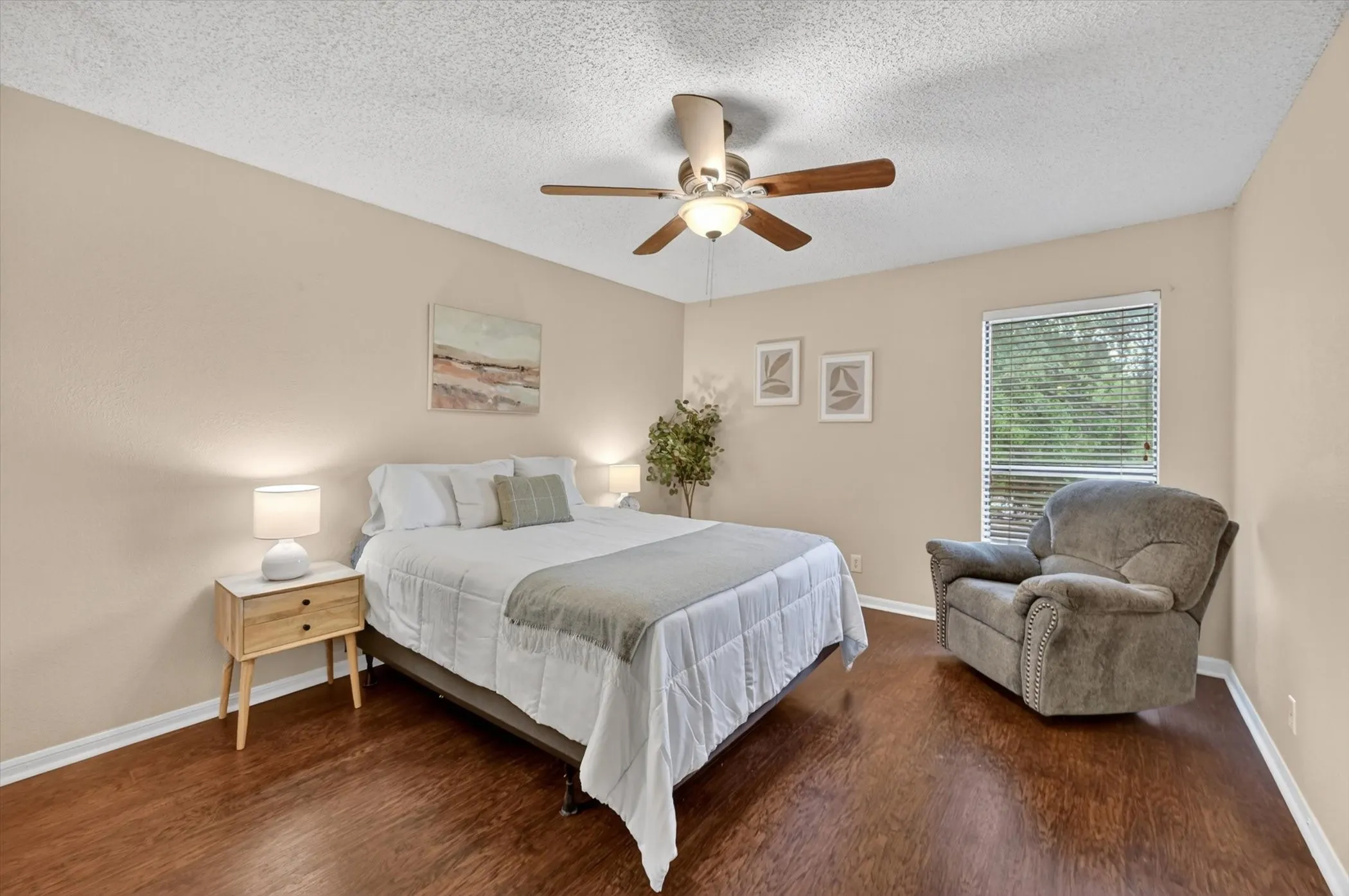 Bedroom featuring wood-finish flooring, neutral-toned walls, a ceiling fan with integrated lighting, and a window with horizontal blinds