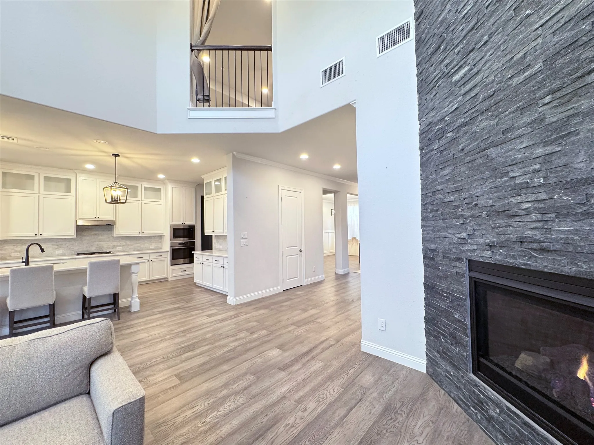 Open-concept living area featuring a stone-clad fireplace and wood-finish flooring