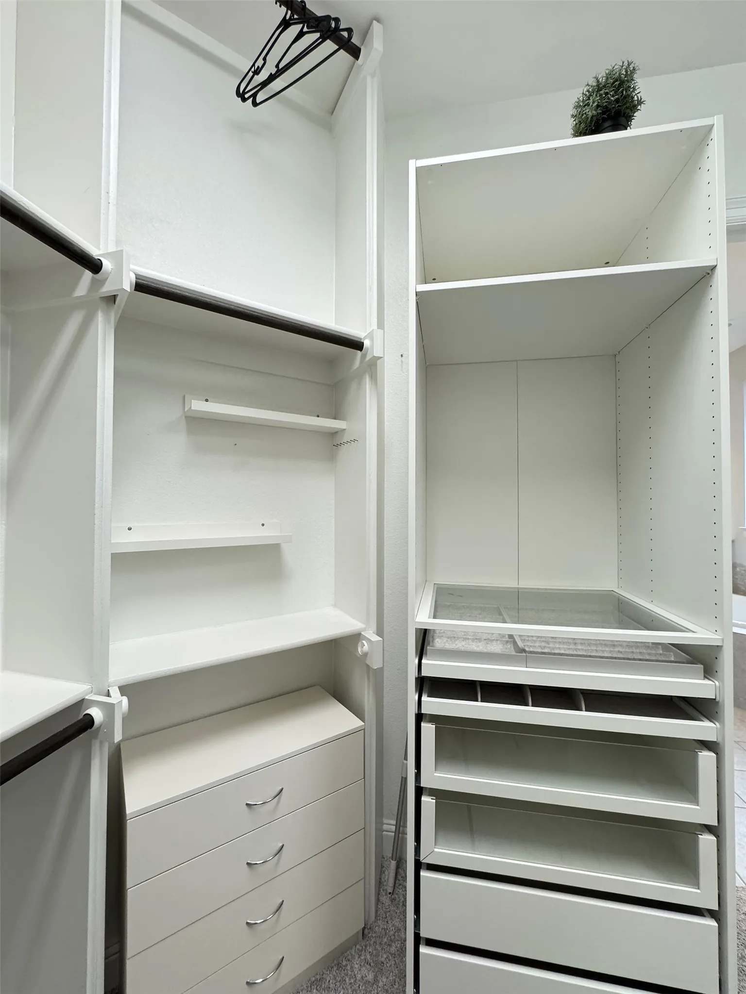 Custom closet system featuring white cabinetry and multiple hanging rods
