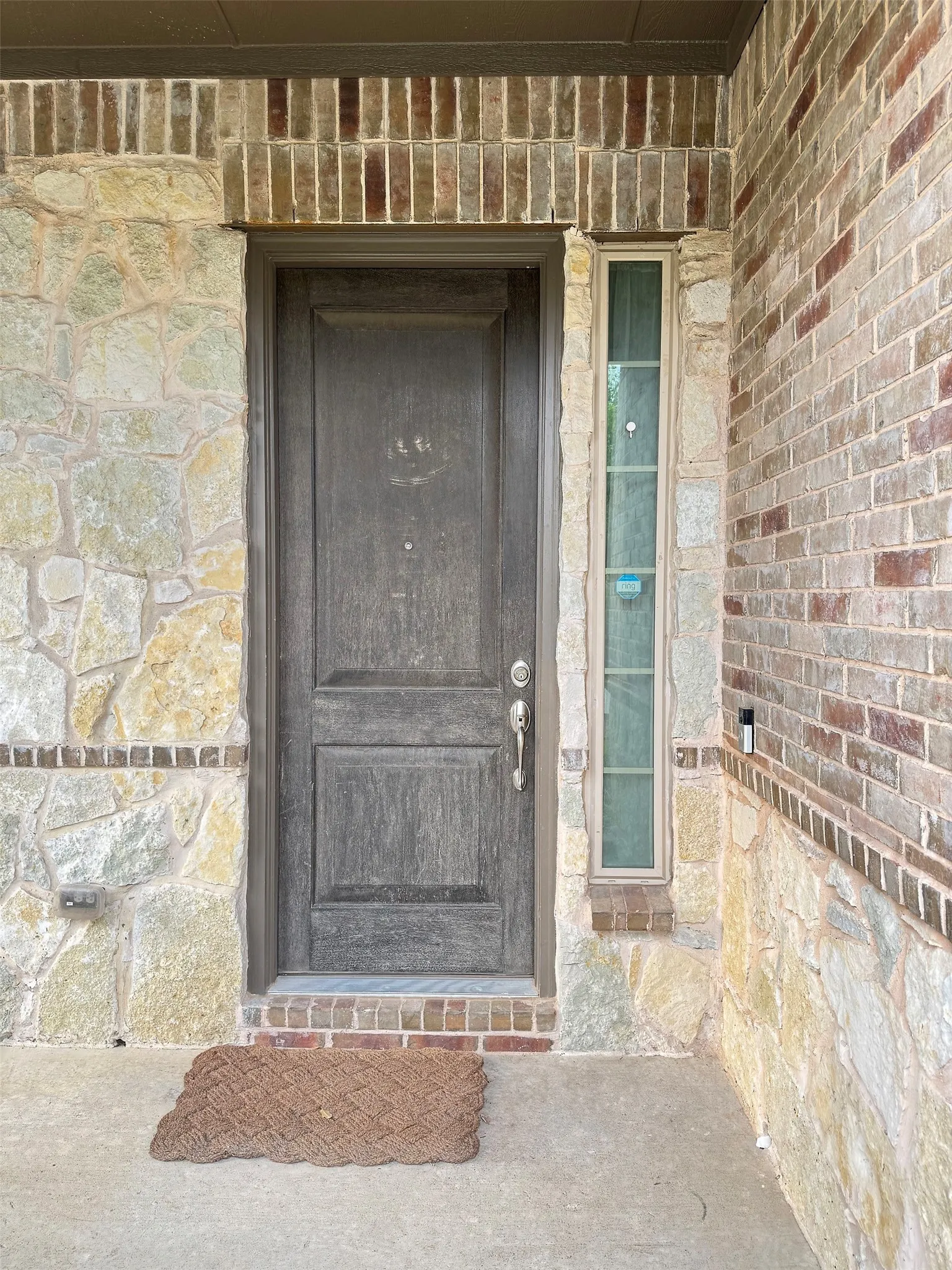 Exterior entrance featuring a paneled door, stone facade, brick details, and a vertical frosted glass window