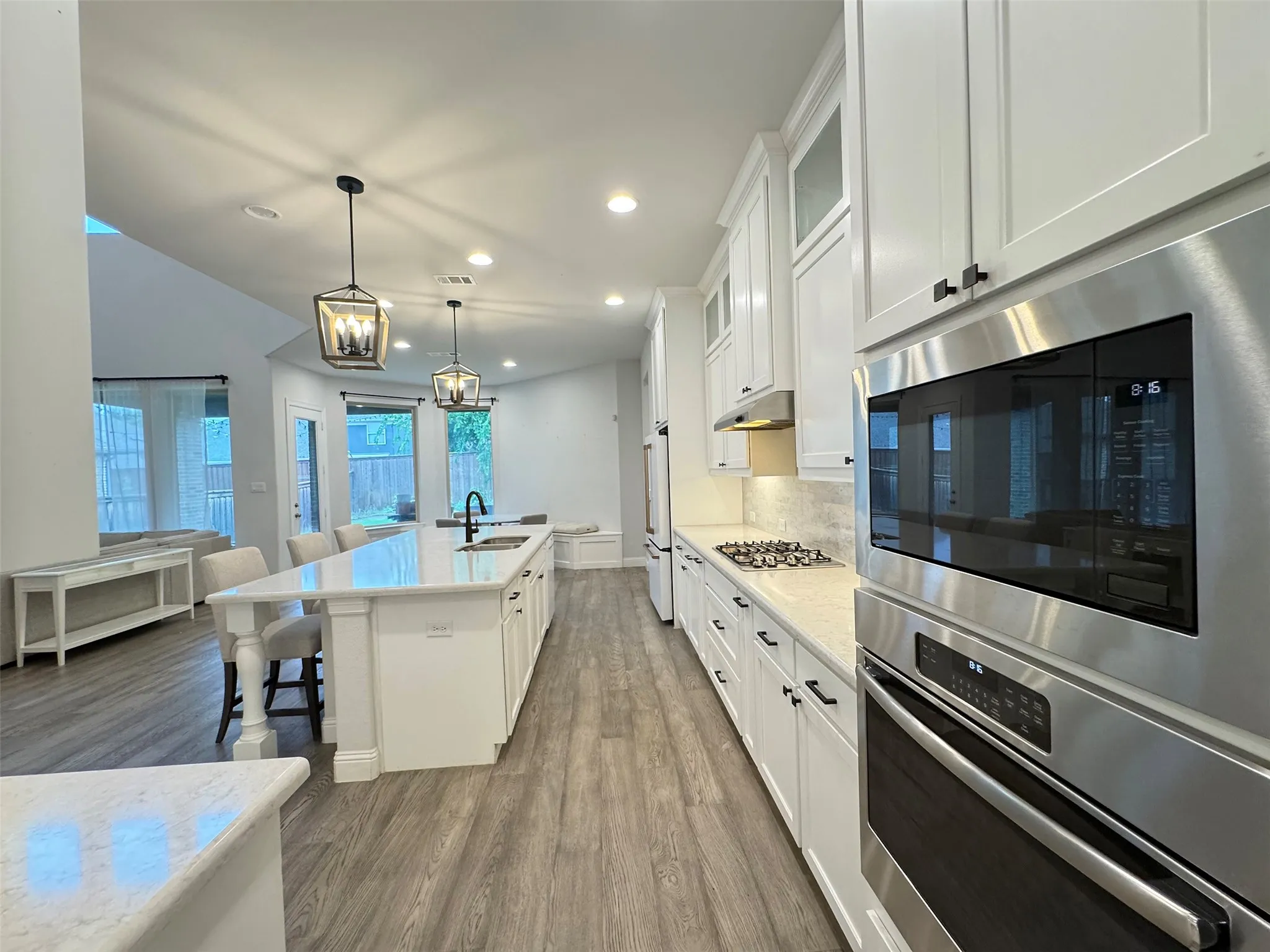 Kitchen featuring a central island with countertop seating, white shaker cabinetry, stainless steel appliances, a gas cooktop, and wood-finish flooring