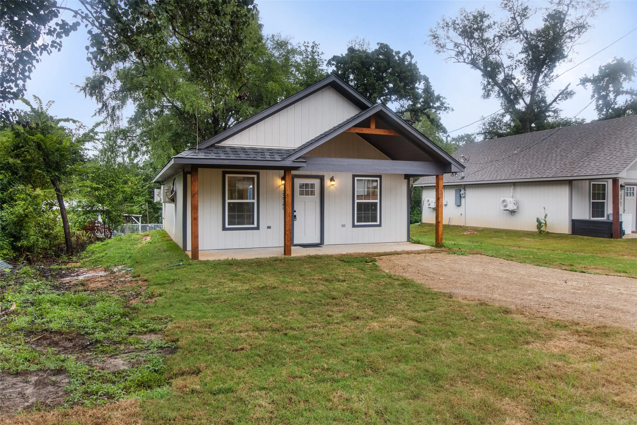Modern farmhouse-style exterior with white siding, dark trim, a covered porch, wood beam accents, and a front lawn
