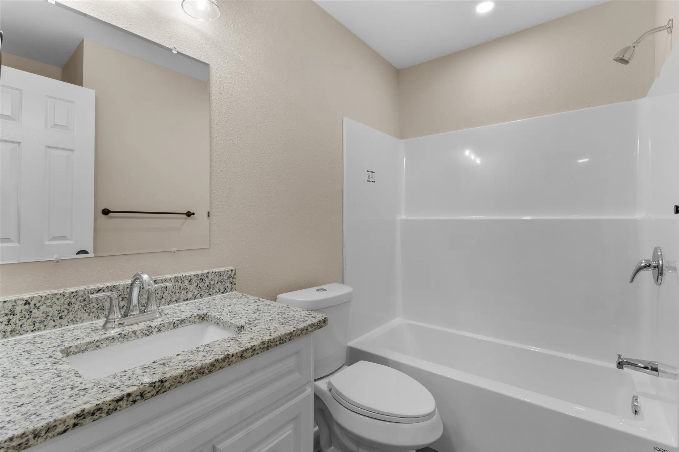 Bathroom featuring a white vanity with a speckled countertop, undermount sink, and chrome faucet