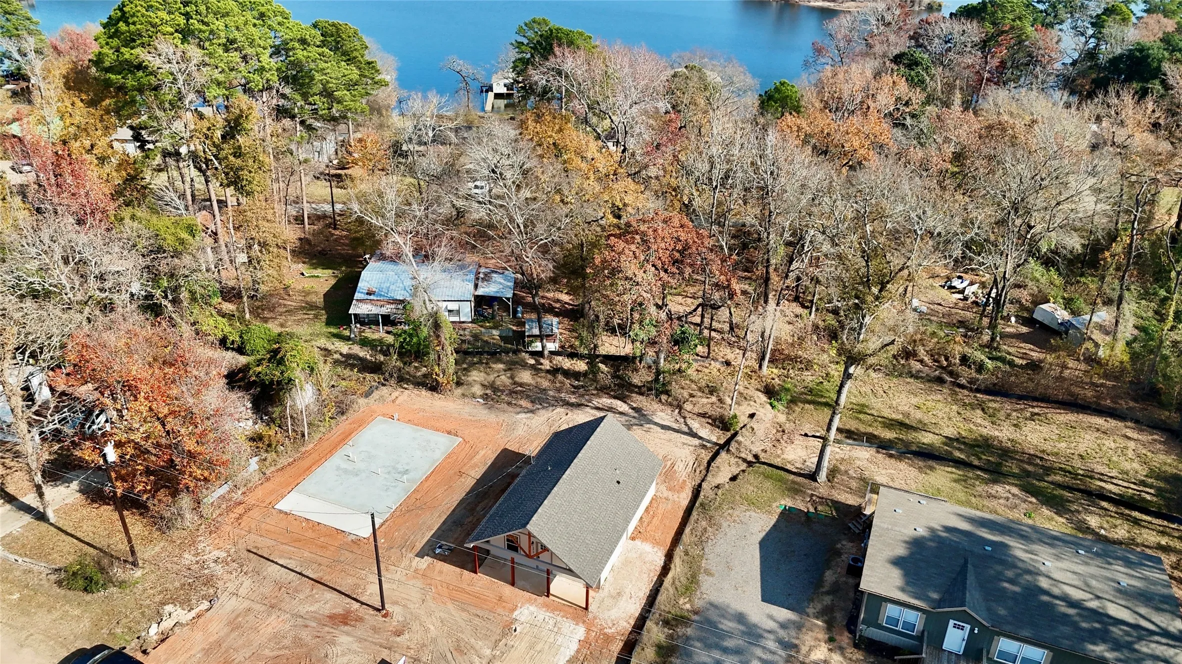 New construction building with a gray shingle roof, a rectangular concrete slab, and a cleared building site