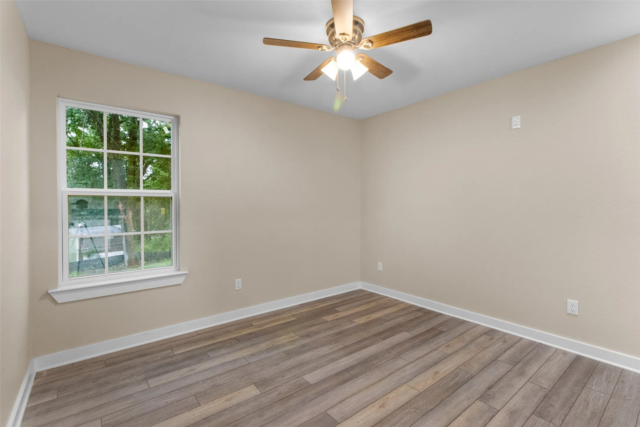Interior room featuring wood-finish flooring, light neutral-toned walls, and white baseboards