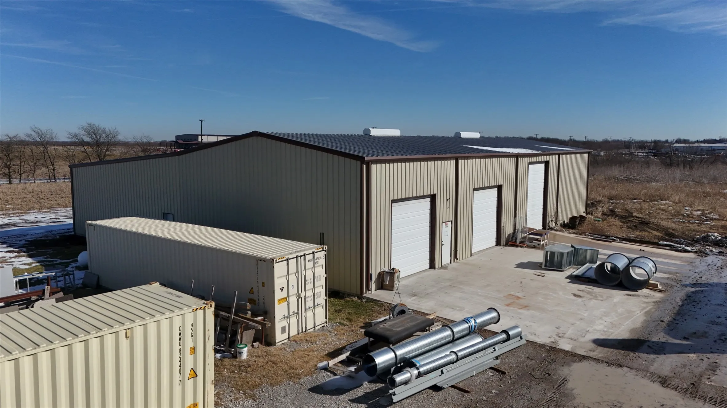 Industrial-style building featuring a metal roof and two large roll-up doors