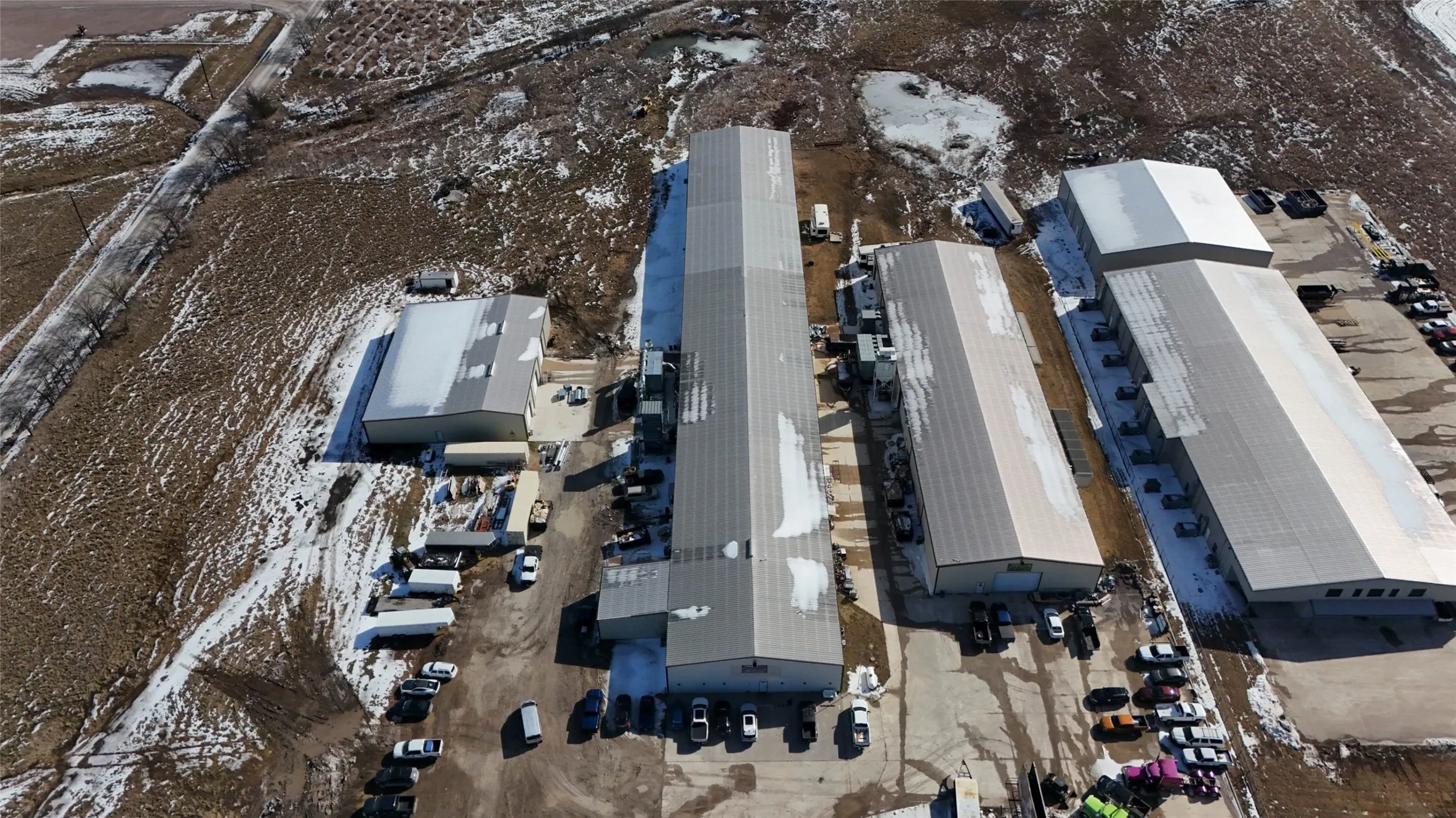 Extensive commercial property featuring multiple large industrial buildings with metal roofs and surrounding paved parking areas