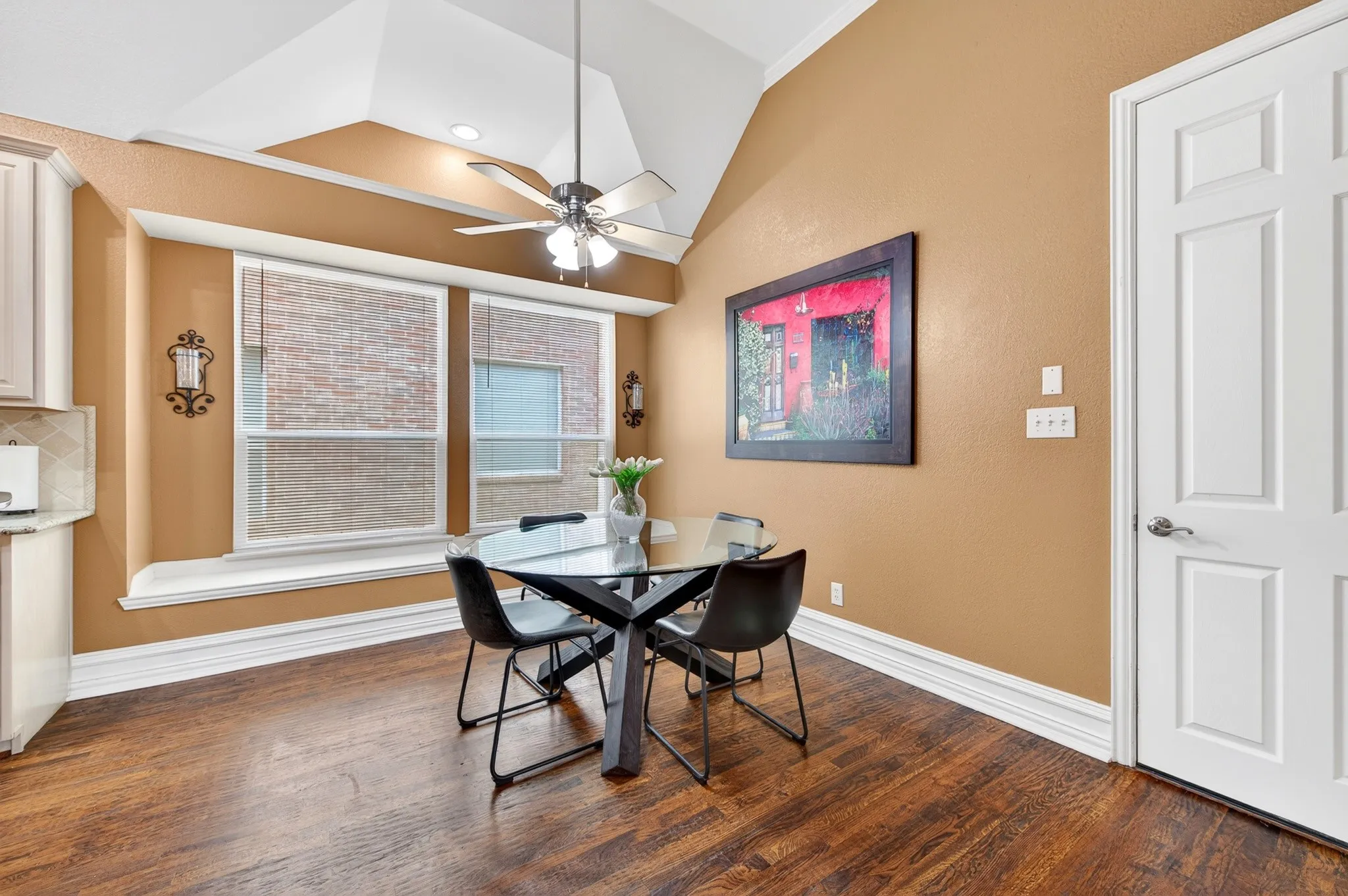 Dining area featuring wood-finish flooring, vaulted ceilings, and a ceiling fan