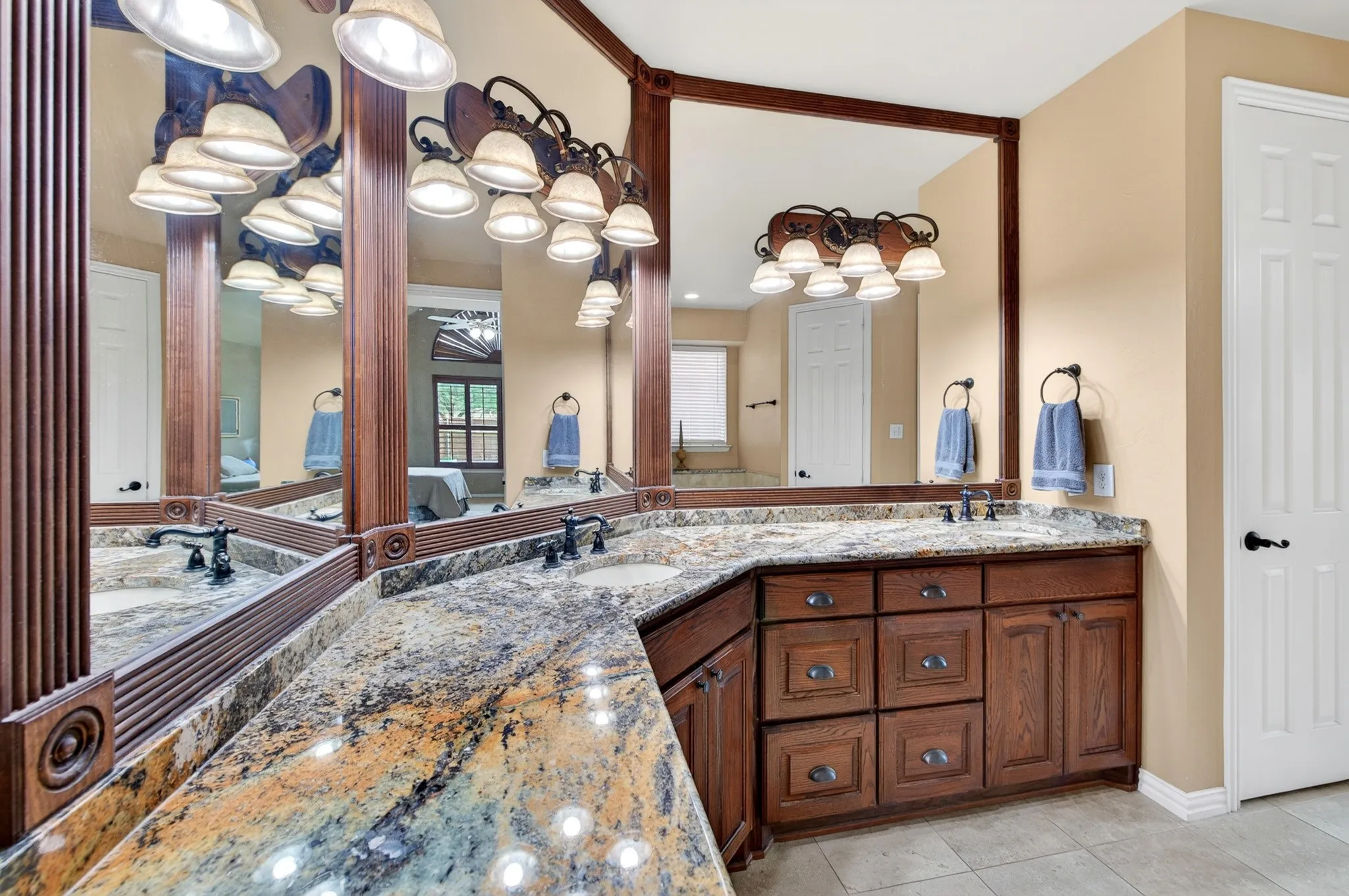 Double vanity with integrated sinks, granite countertops, extensive wood cabinetry, and framed mirrors