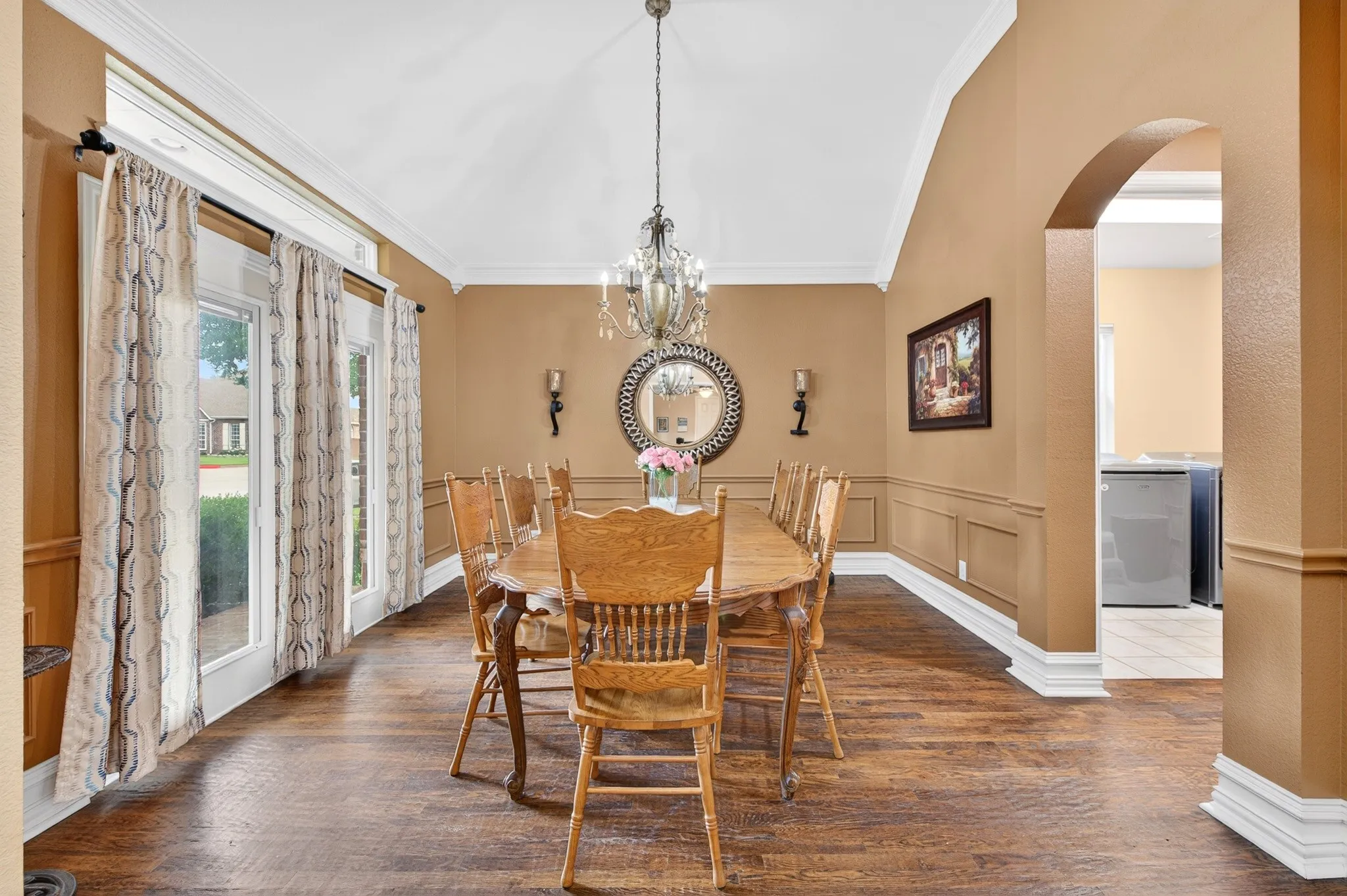 Formal dining area featuring wood-finish flooring, wainscoting, and an arched entryway