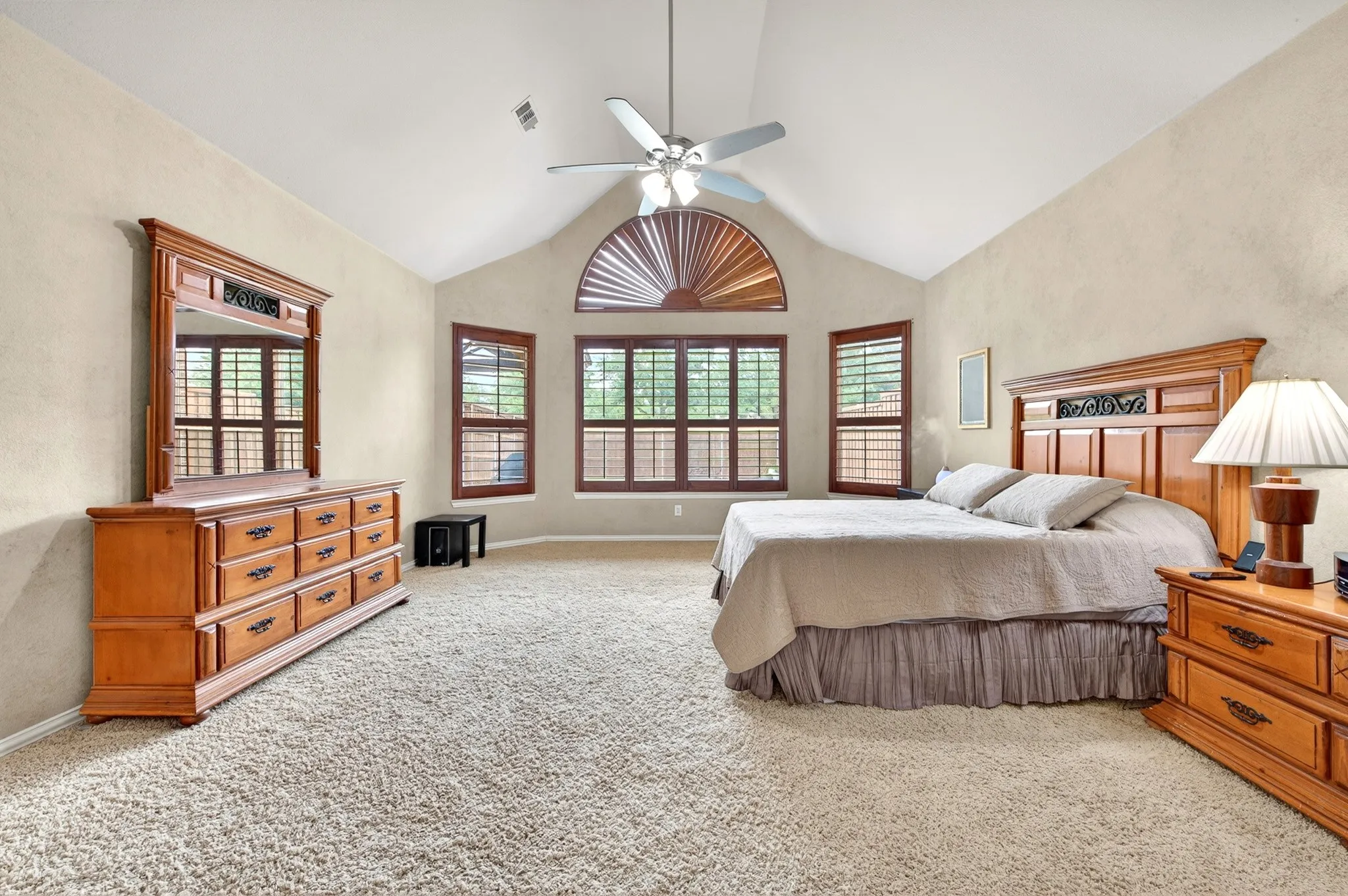 Spacious room featuring a vaulted ceiling and an arched transom window
