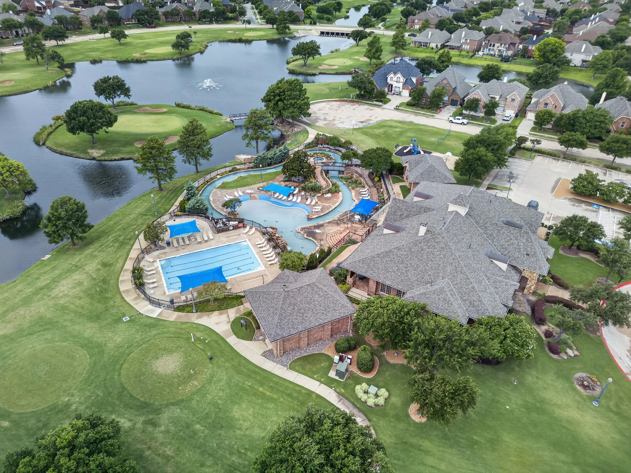 Community amenity center featuring multiple pools, a winding lazy river, and extensive patio areas