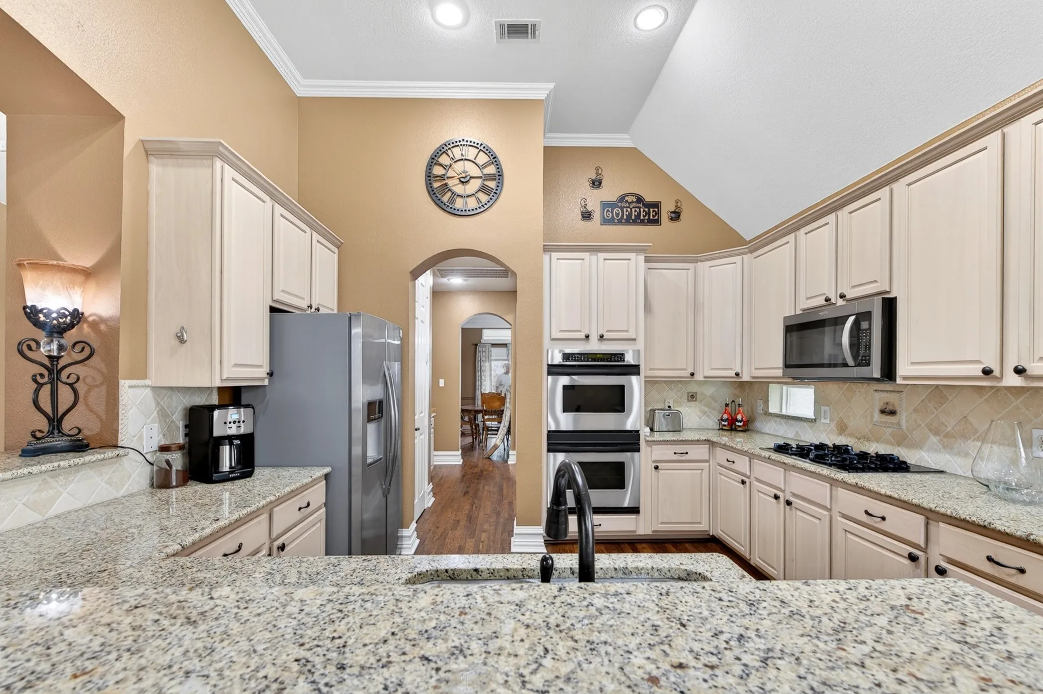 Kitchen featuring granite-finish countertops, light-toned cabinetry, stainless steel appliances including a built-in microwave, double wall ovens, and a gas cooktop