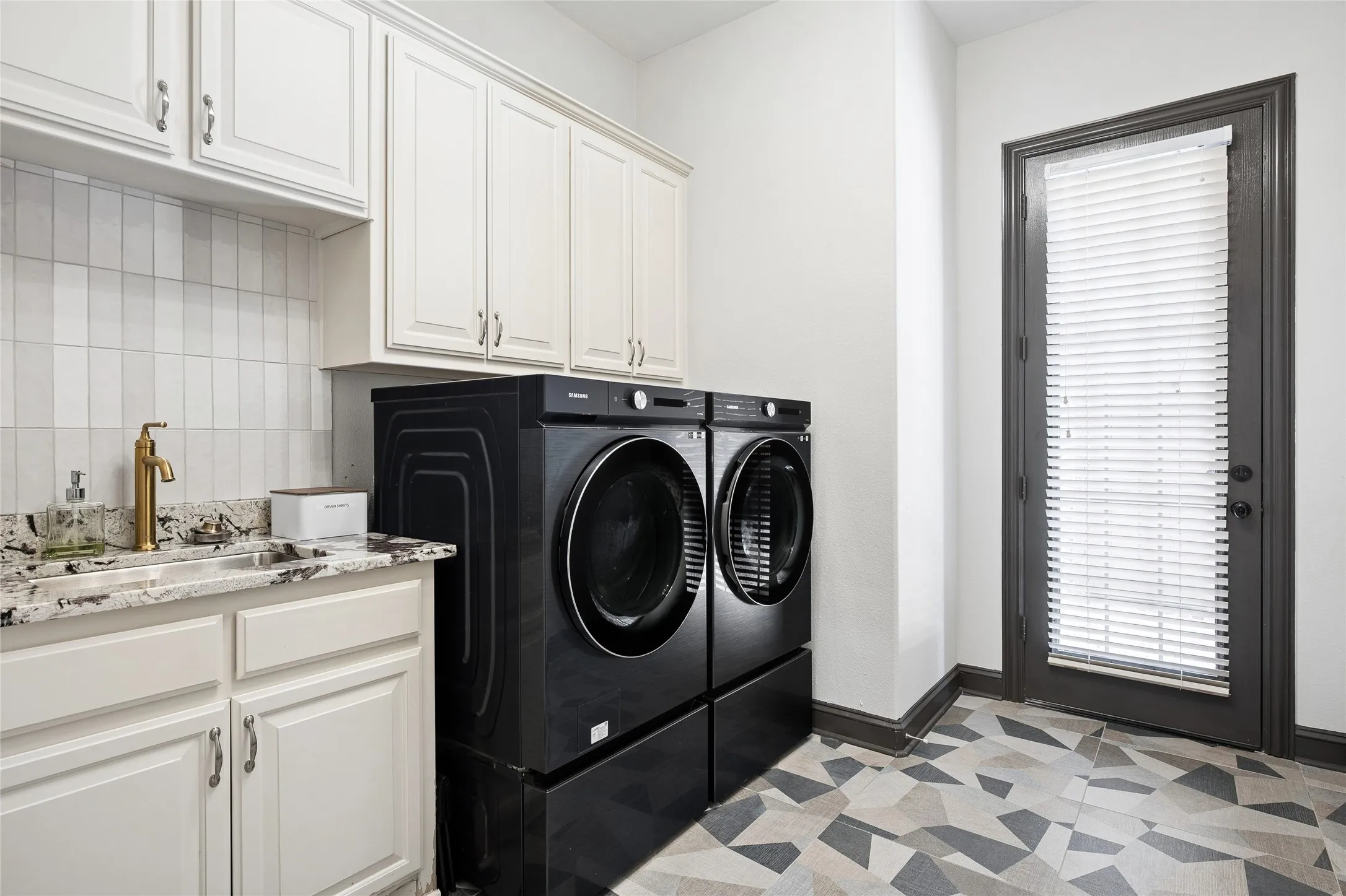 Laundry with modern, fun tile flooring, quartz counter for sink and door leads to breezeway to the seperate 3rd car garage. Wonderful cabinets!