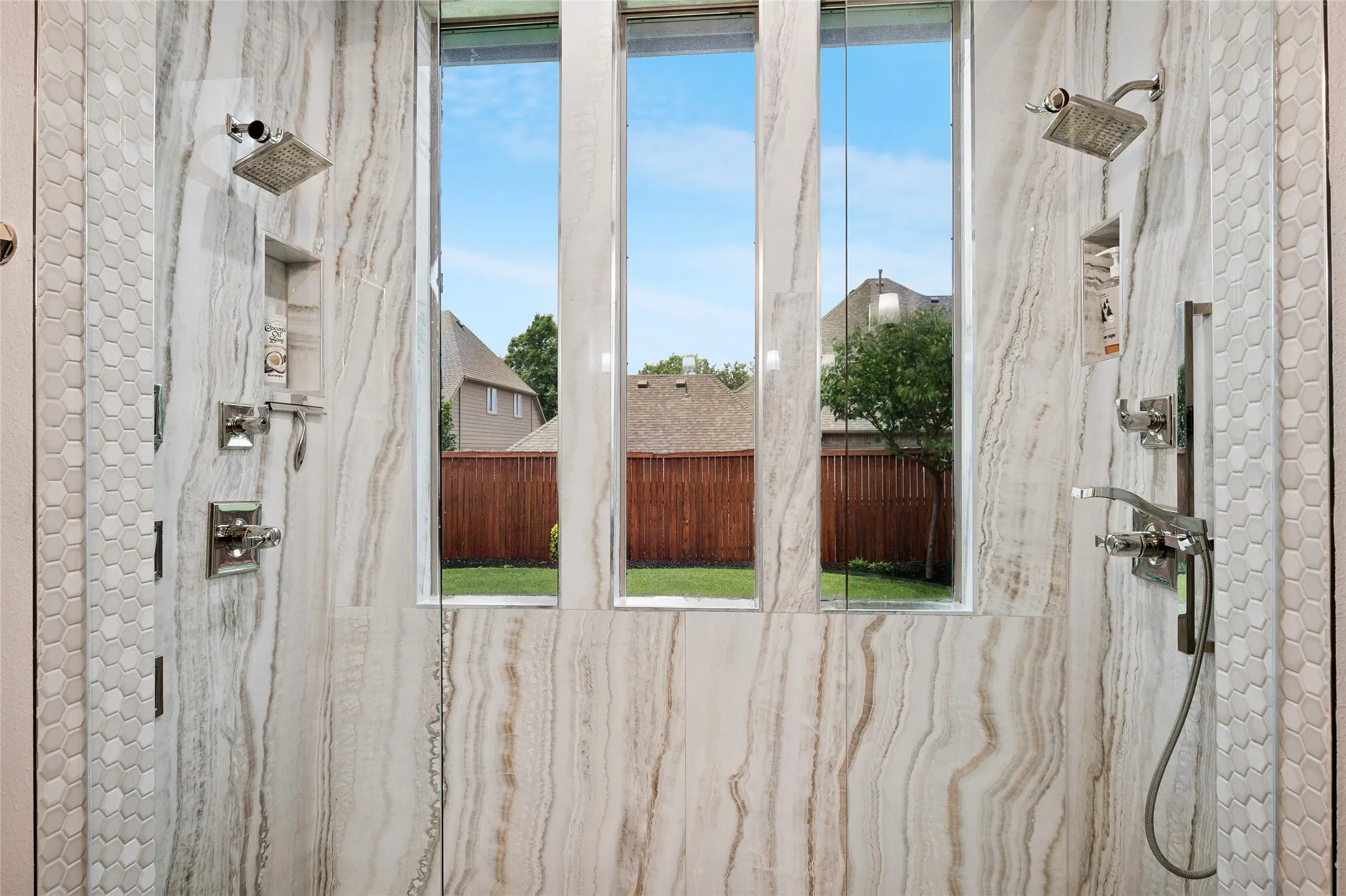 Walk-in shower with dual heads and hand-held spray.