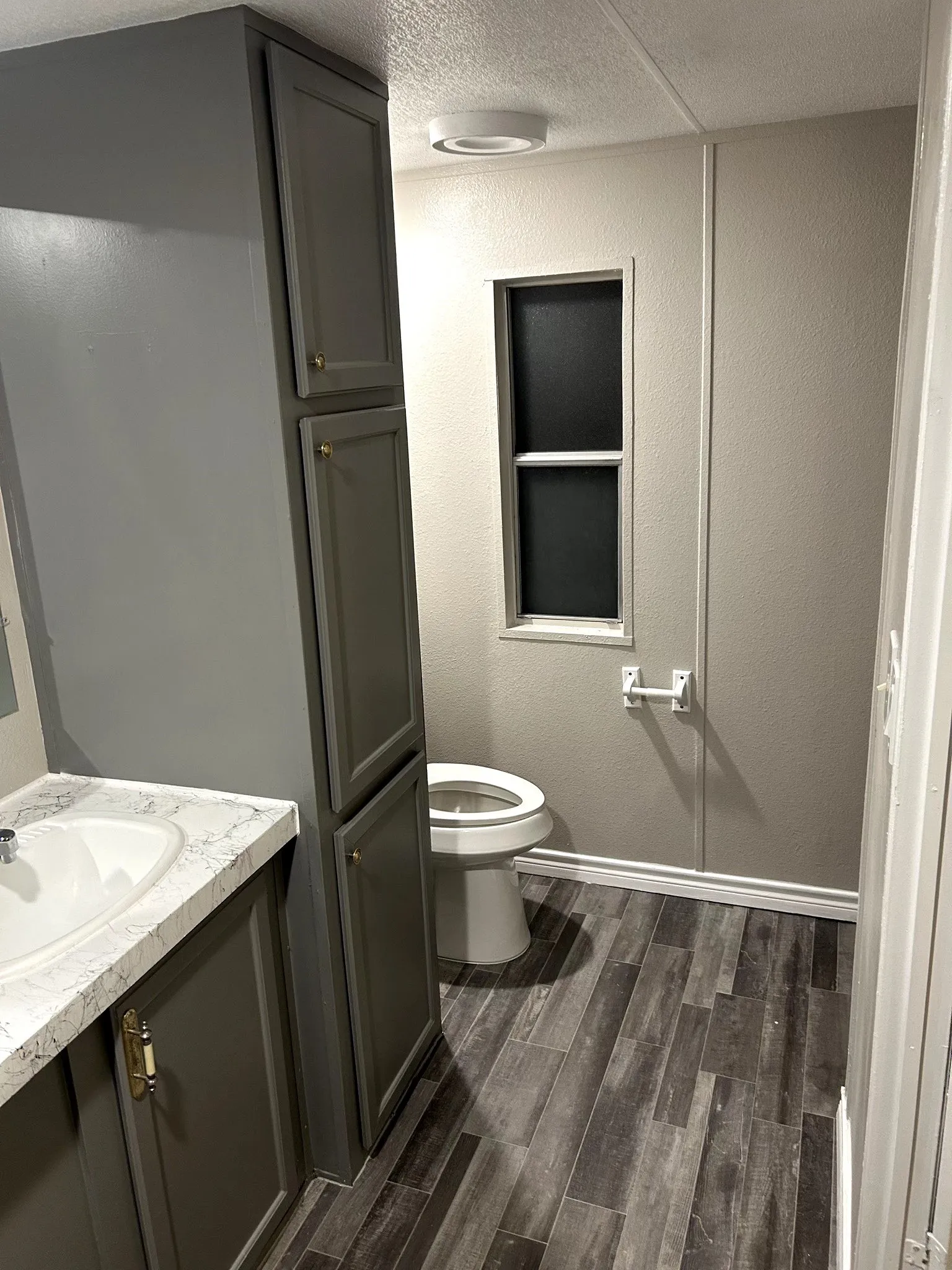 Bathroom vanity with a white countertop and integrated sink, complemented by gray cabinetry