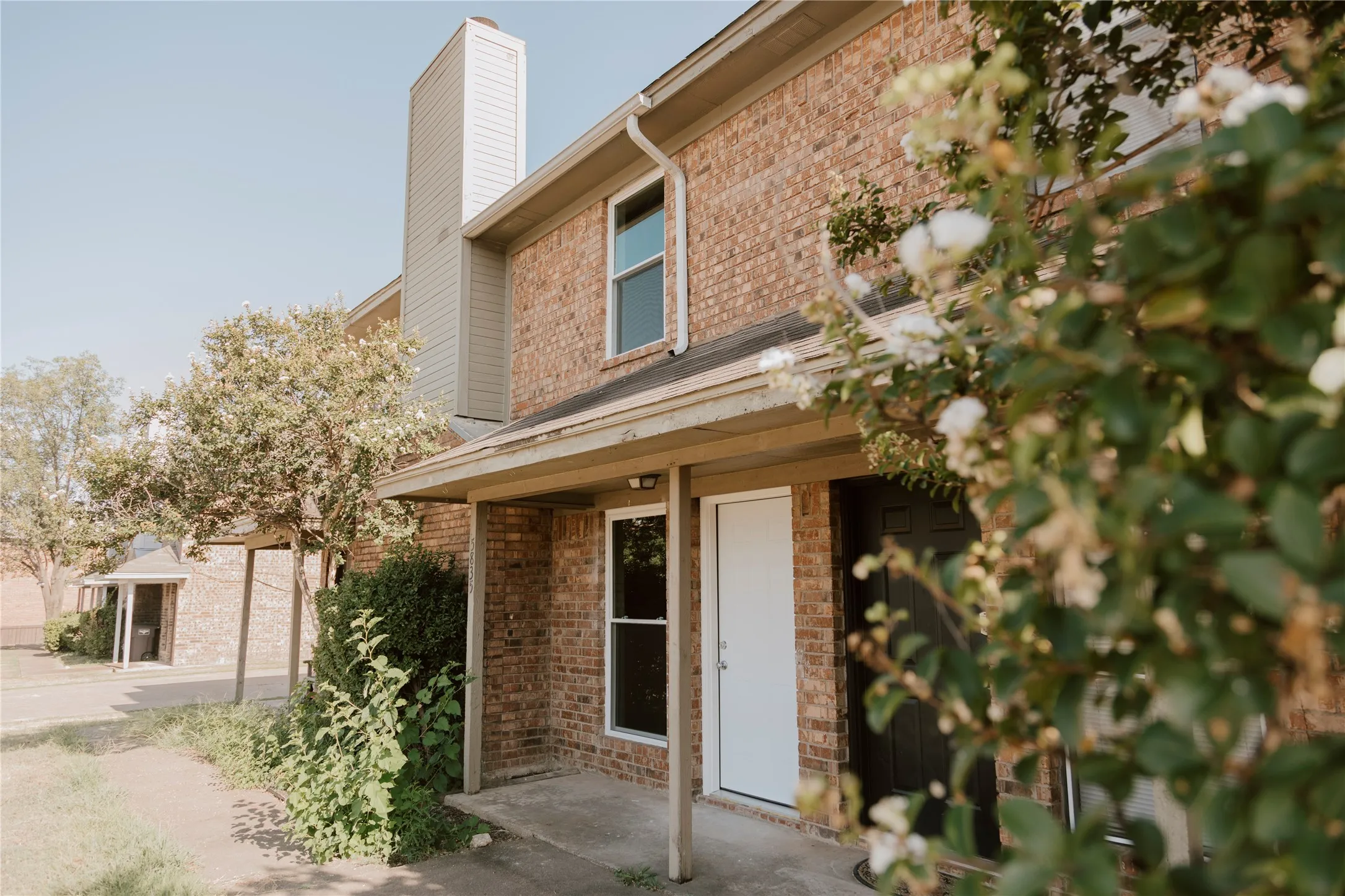Brick exterior with a covered entryway, white front door, and dark second door
