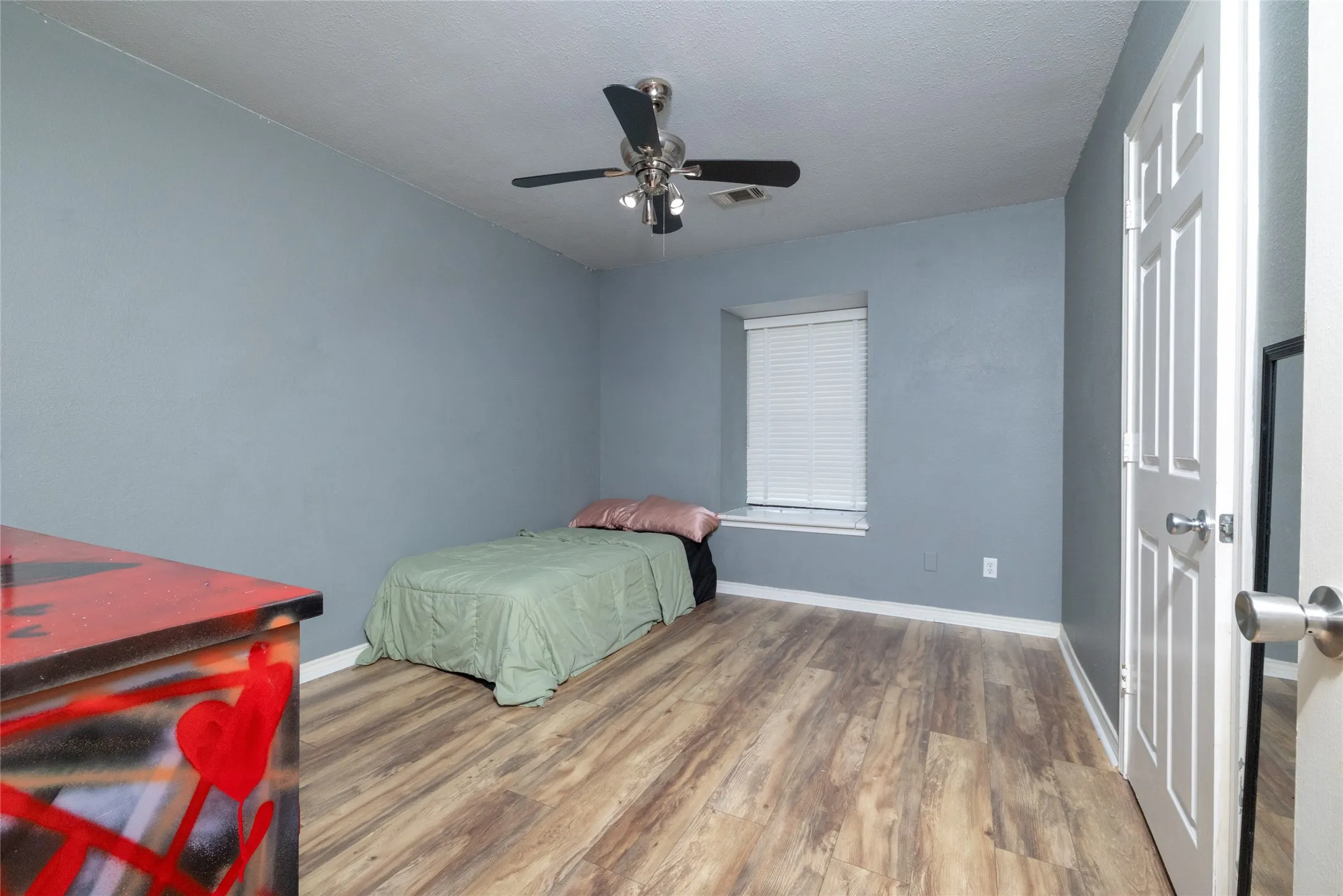 Room featuring wood-look flooring, a window with blinds, and a ceiling fan with integrated lighting