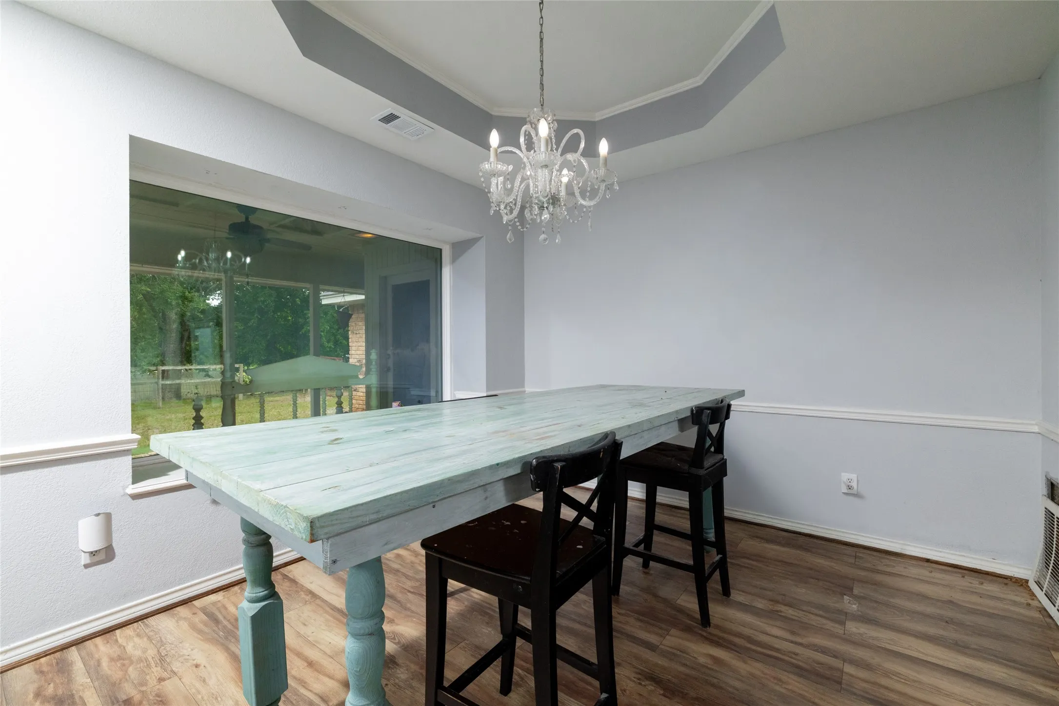 Dining area featuring laminate wood-look flooring, a tray ceiling, and a decorative chandelier