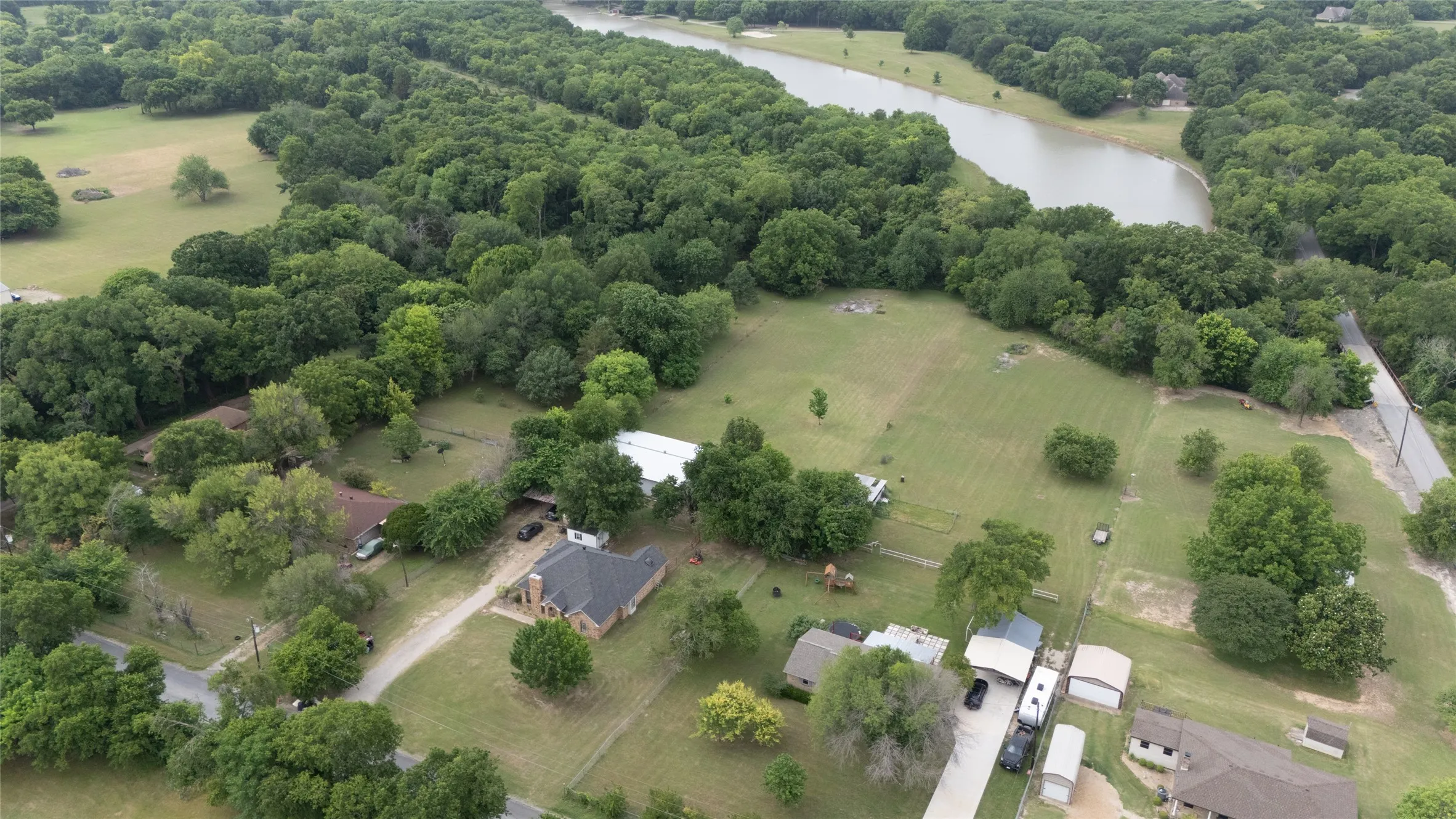 Expansive aerial showcasing a residential property with a surrounding landscape of mature trees and open green spaces