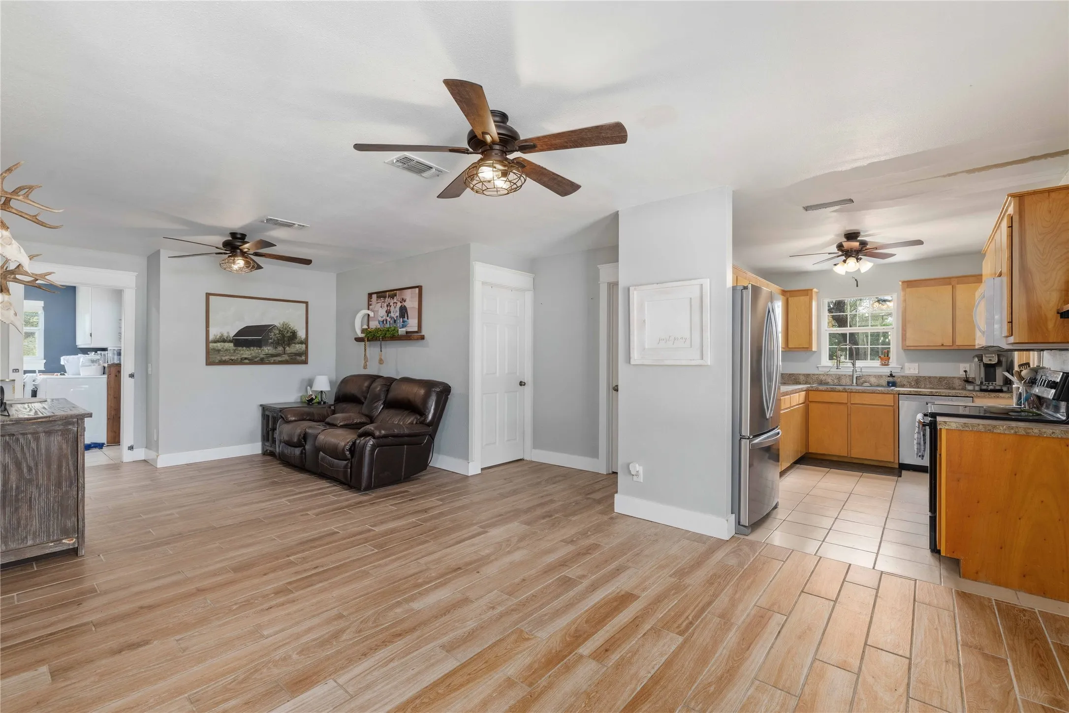 Open-concept living area with wood-finish flooring, light grey wall paint, and multiple ceiling fans