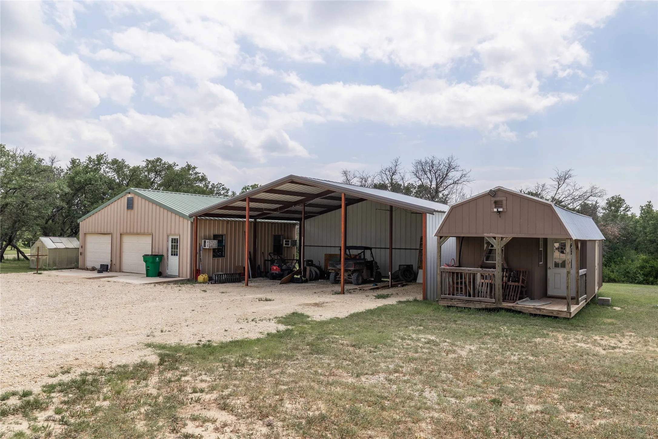 Metal-sided multi-bay garage with overhead doors and an attached open-sided carport
