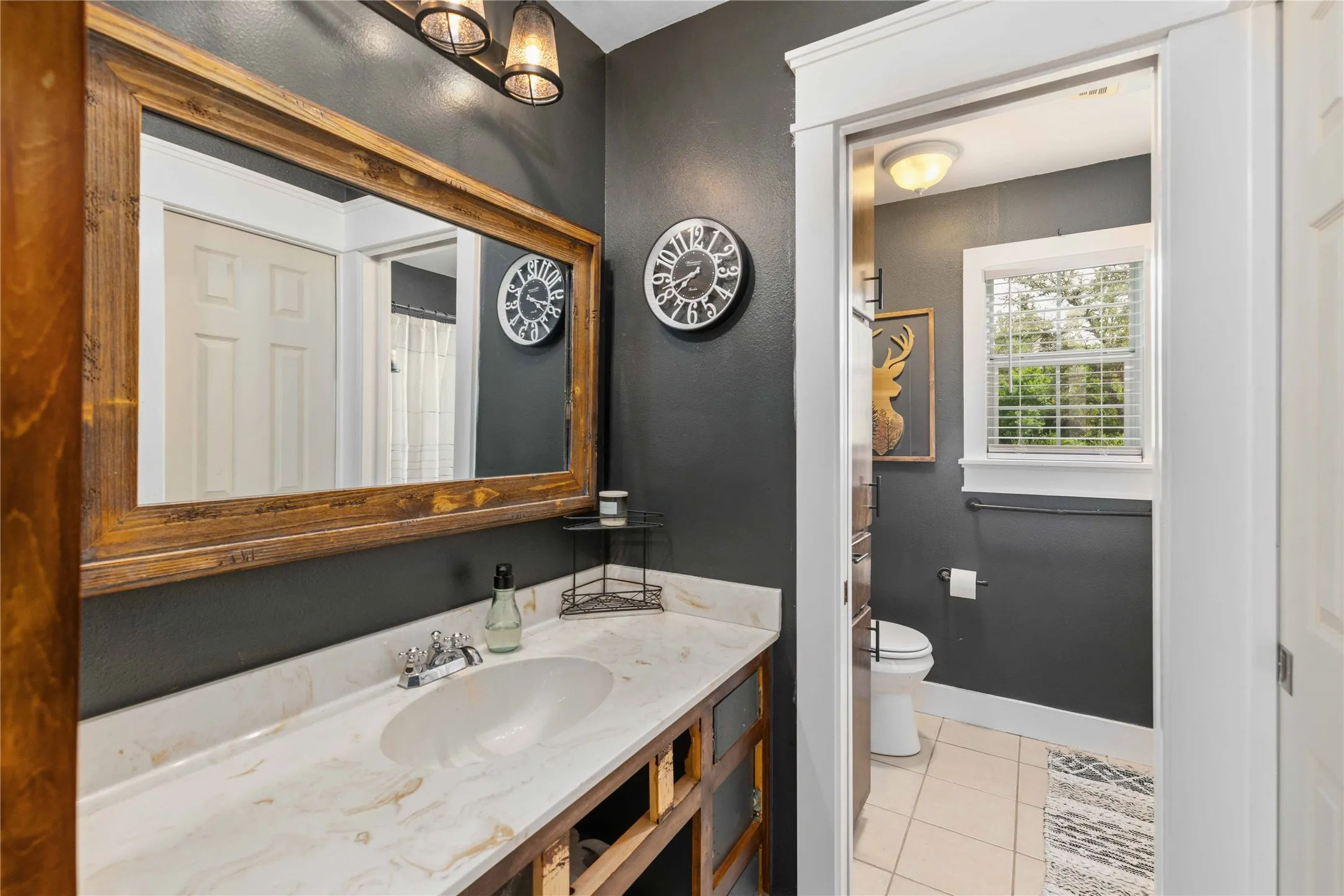 Bathroom featuring a wood-framed mirror, dual overhead light fixtures, and a vanity with an integrated sink and light-toned countertop