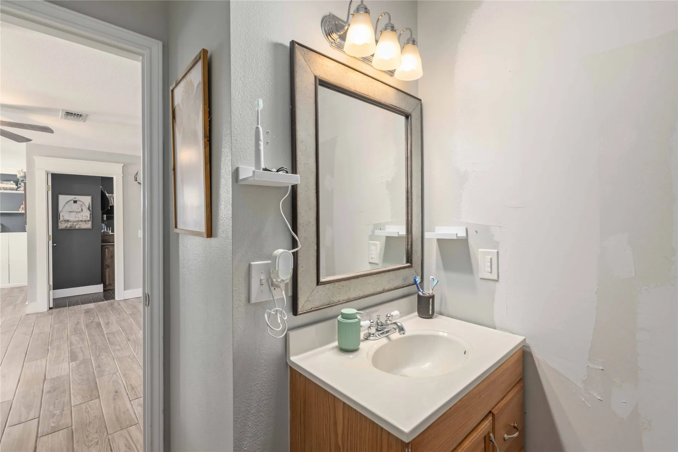Bathroom vanity featuring a light wood-finish cabinet with a white countertop and integrated sink