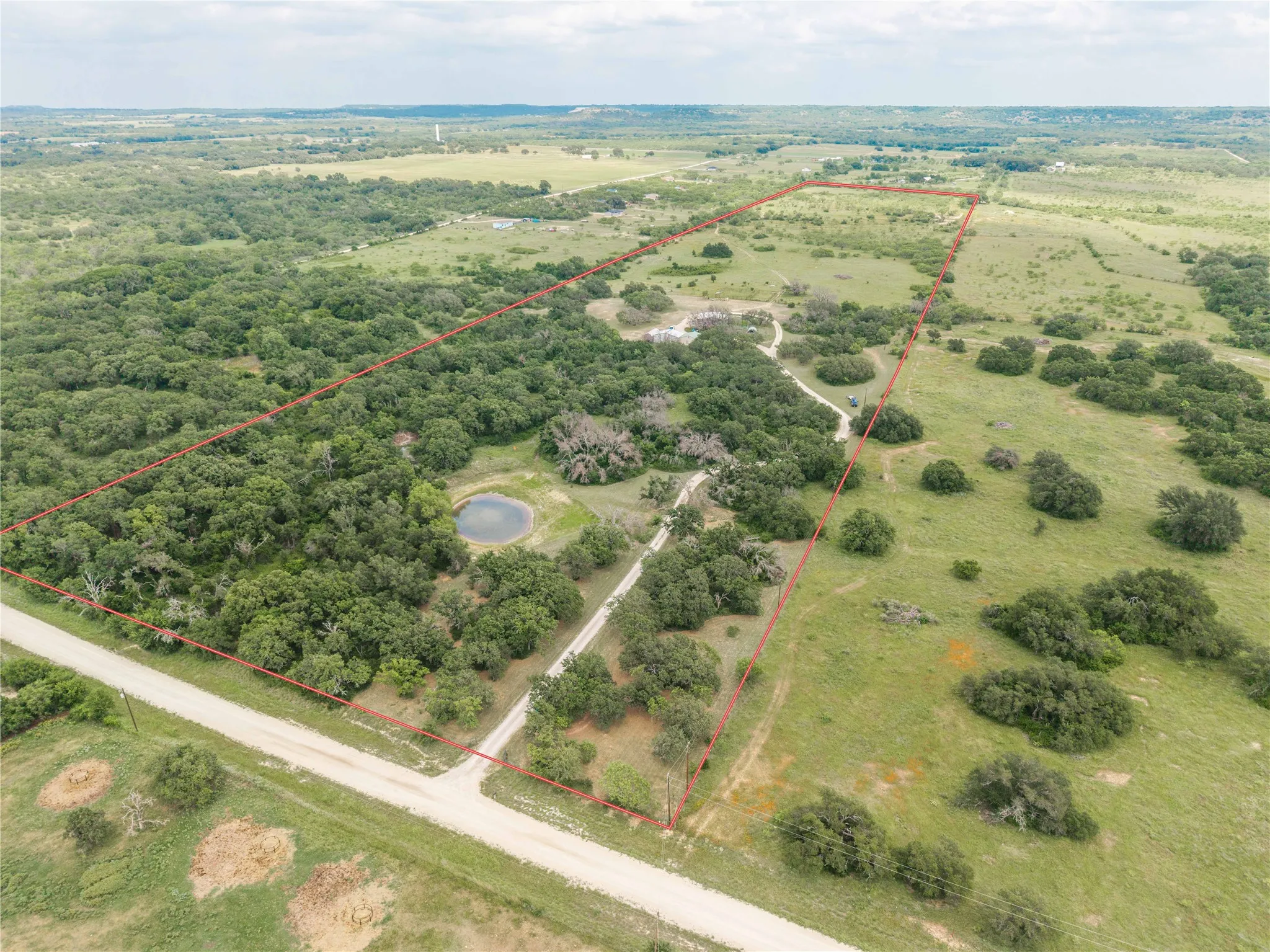 Expansive acreage featuring a private pond, mature trees, open clearings, and perimeter fencing