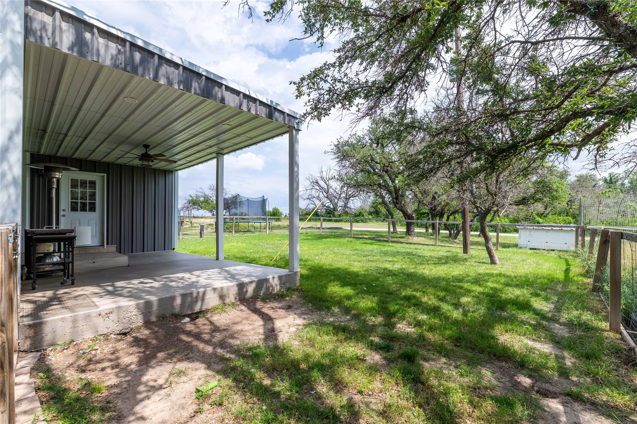 Covered porch featuring a ceiling fan, concrete flooring, and vertical metal siding