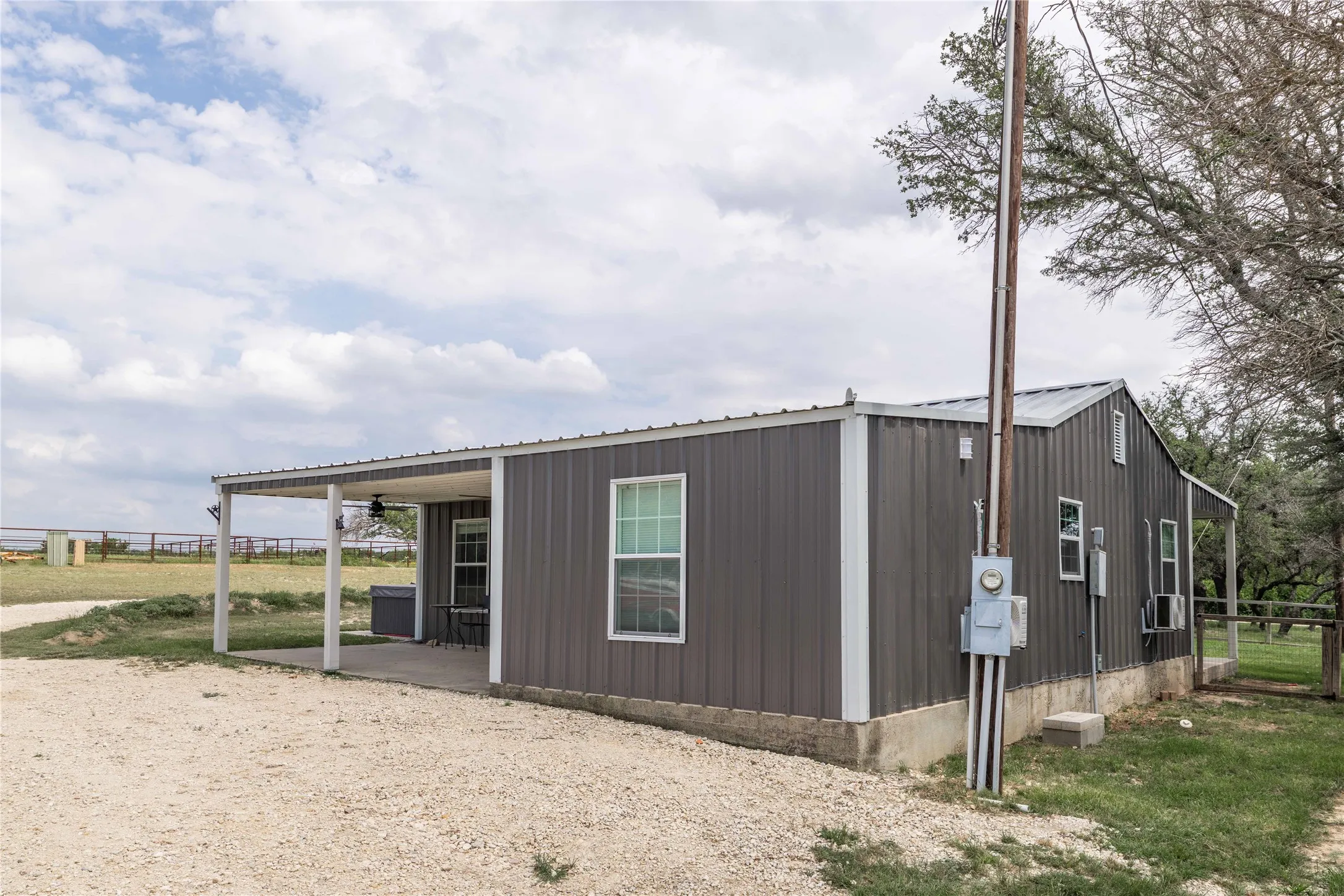 Metal-sided structure featuring a covered concrete patio with a ceiling fan