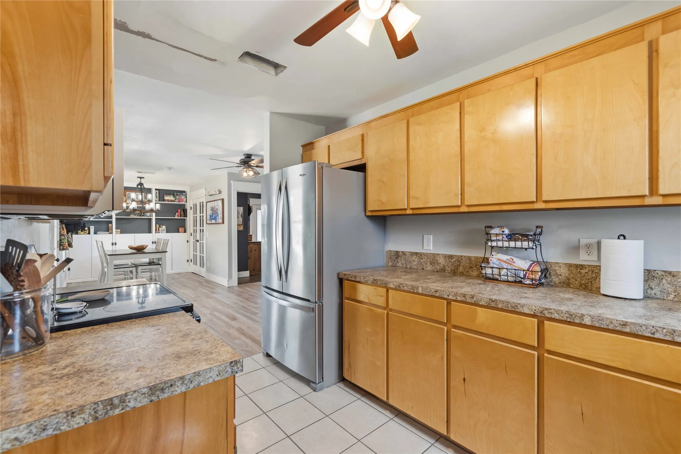 Kitchen featuring wood cabinetry, speckled countertops, and white square floor tiling