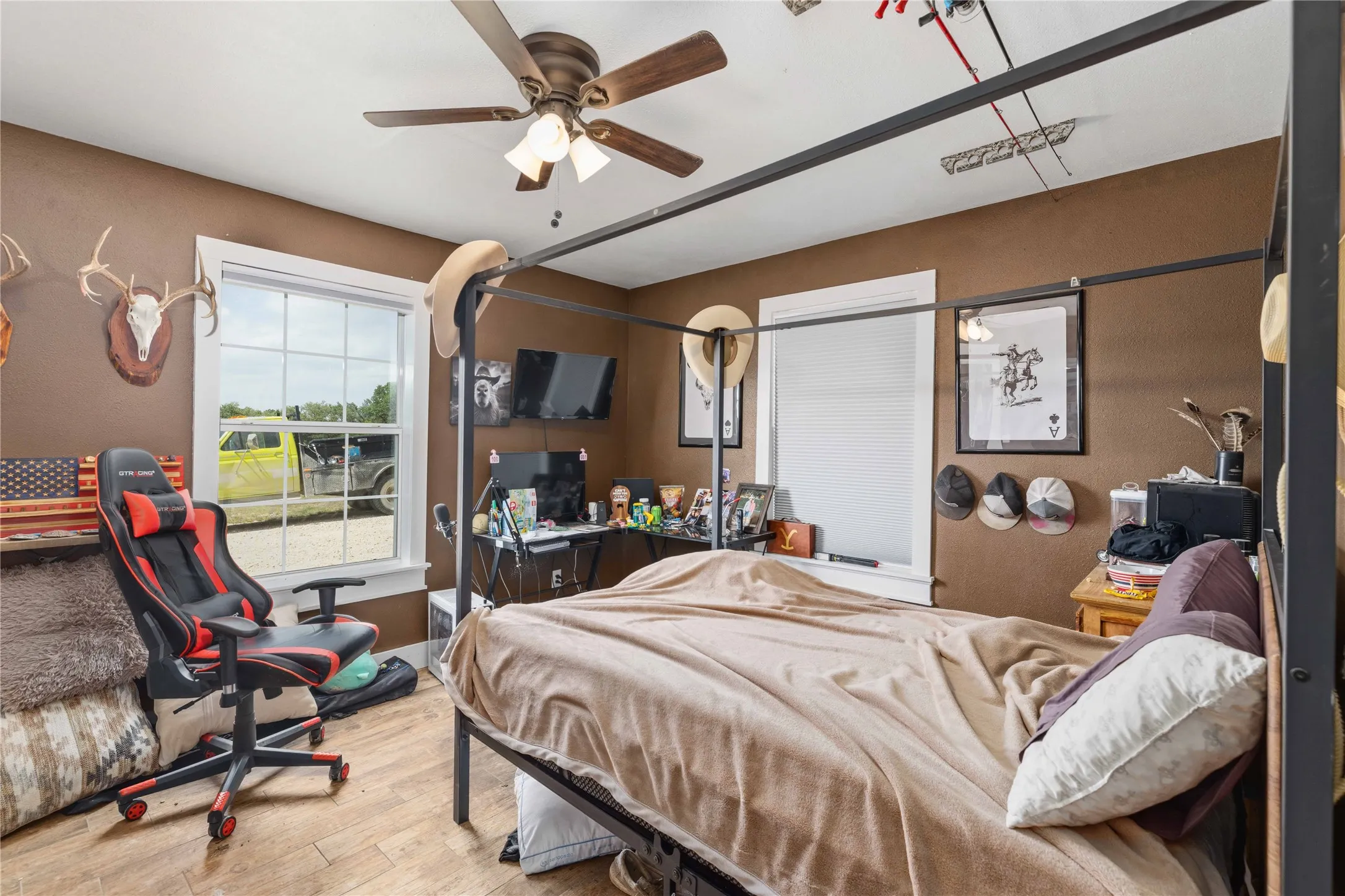 Room featuring wood-finish flooring, a ceiling fan with integrated lighting, and multiple windows with white trim