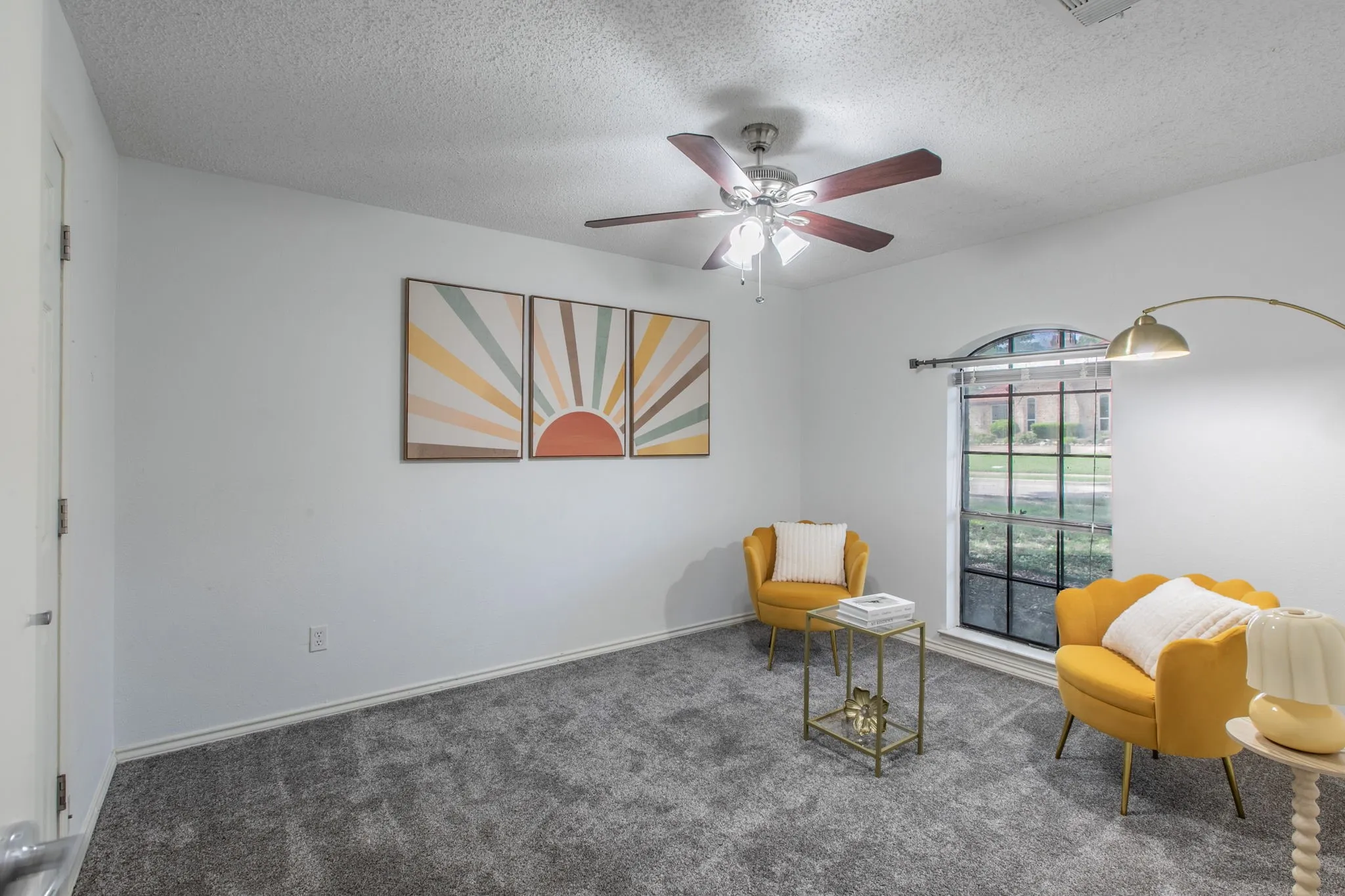 Carpeted room featuring a ceiling fan, arched window, and white walls