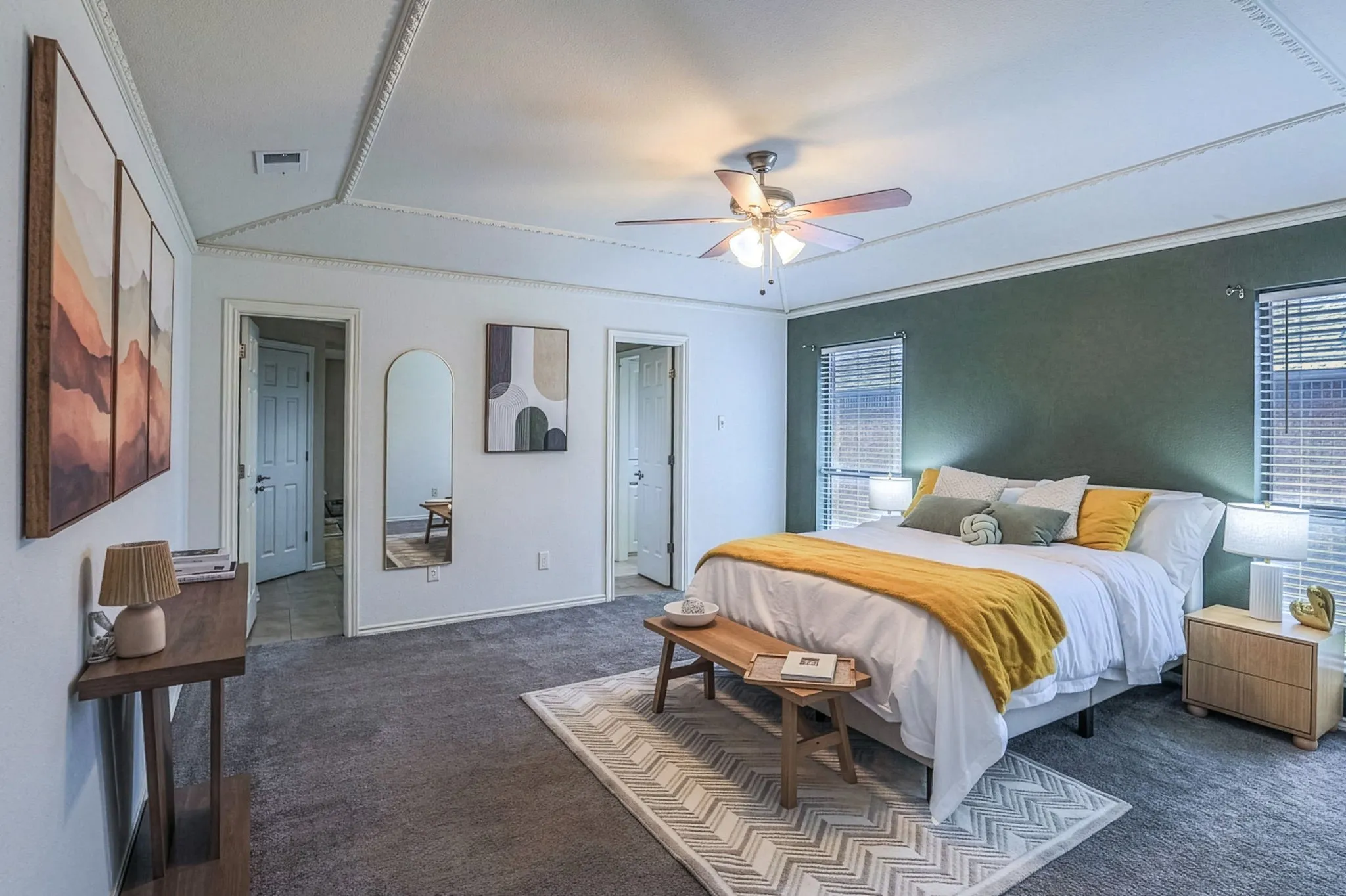 Carpeted room featuring a ceiling fan with integrated lighting, a tray ceiling, and a prominent dark accent wall