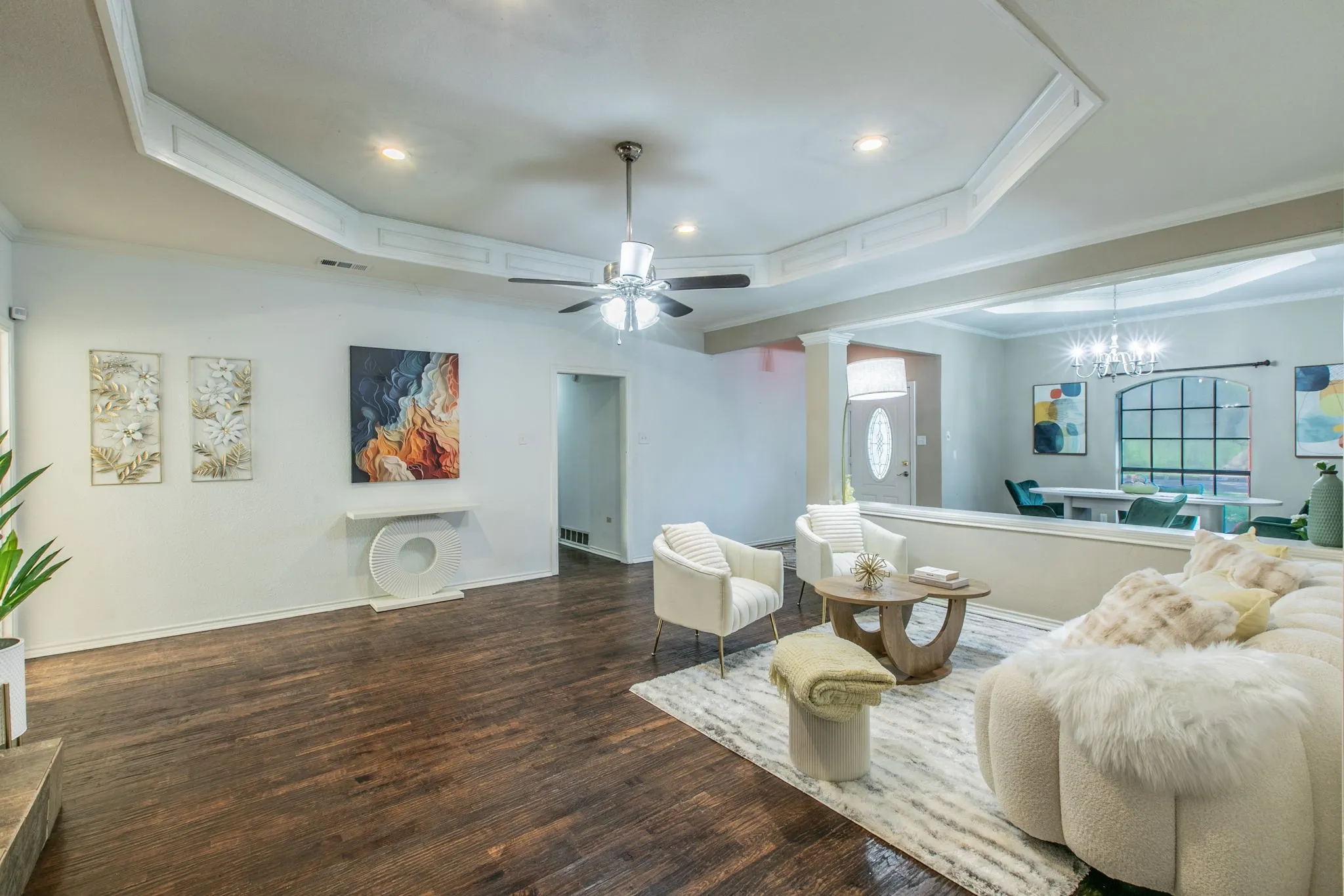 Spacious living area featuring wood-finish flooring, a tray ceiling with recessed lighting and a ceiling fan, and an open concept layout