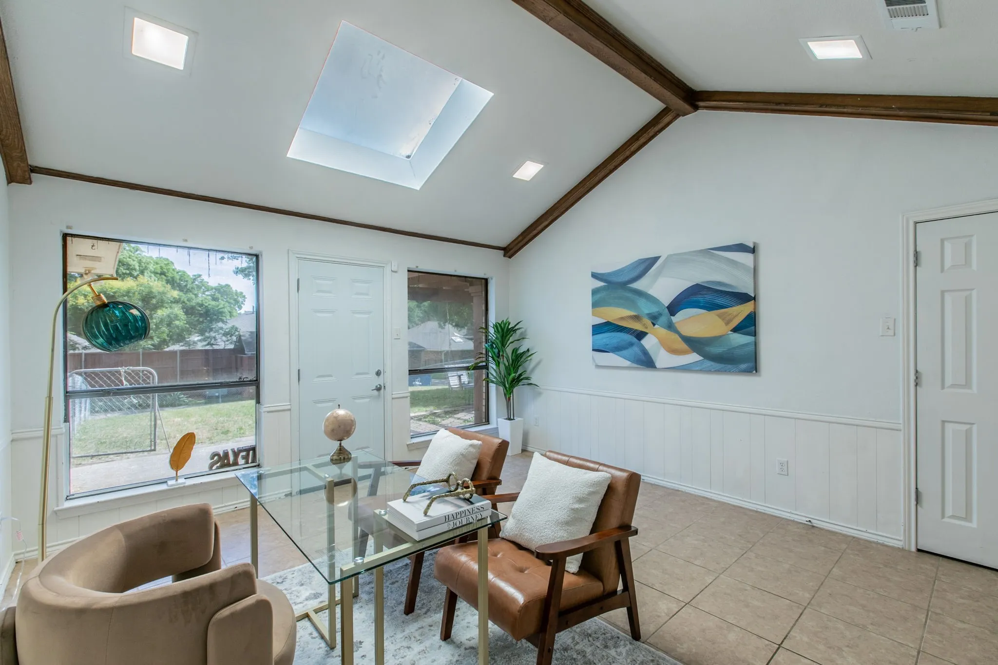 Vaulted ceiling featuring exposed wood beams and a central skylight