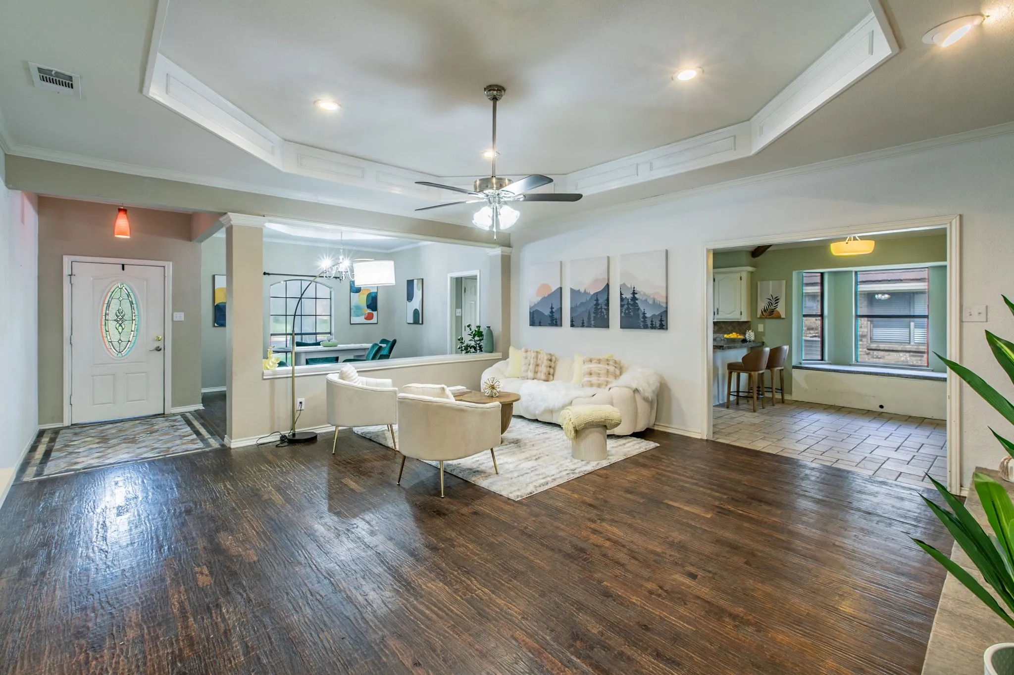 Tray ceiling with recessed lighting and a ceiling fan, complemented by dark wood-finish flooring