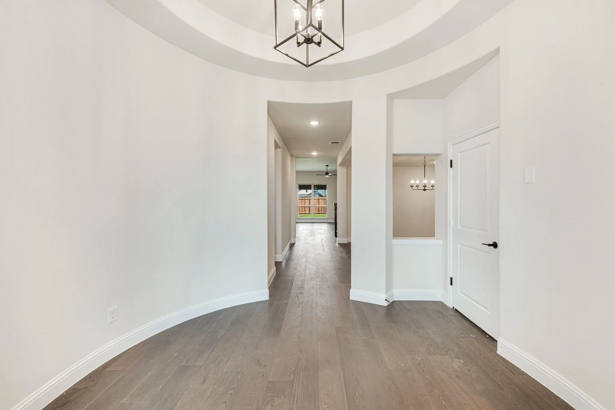 Hallway with a chandelier and dark wood-style flooring
