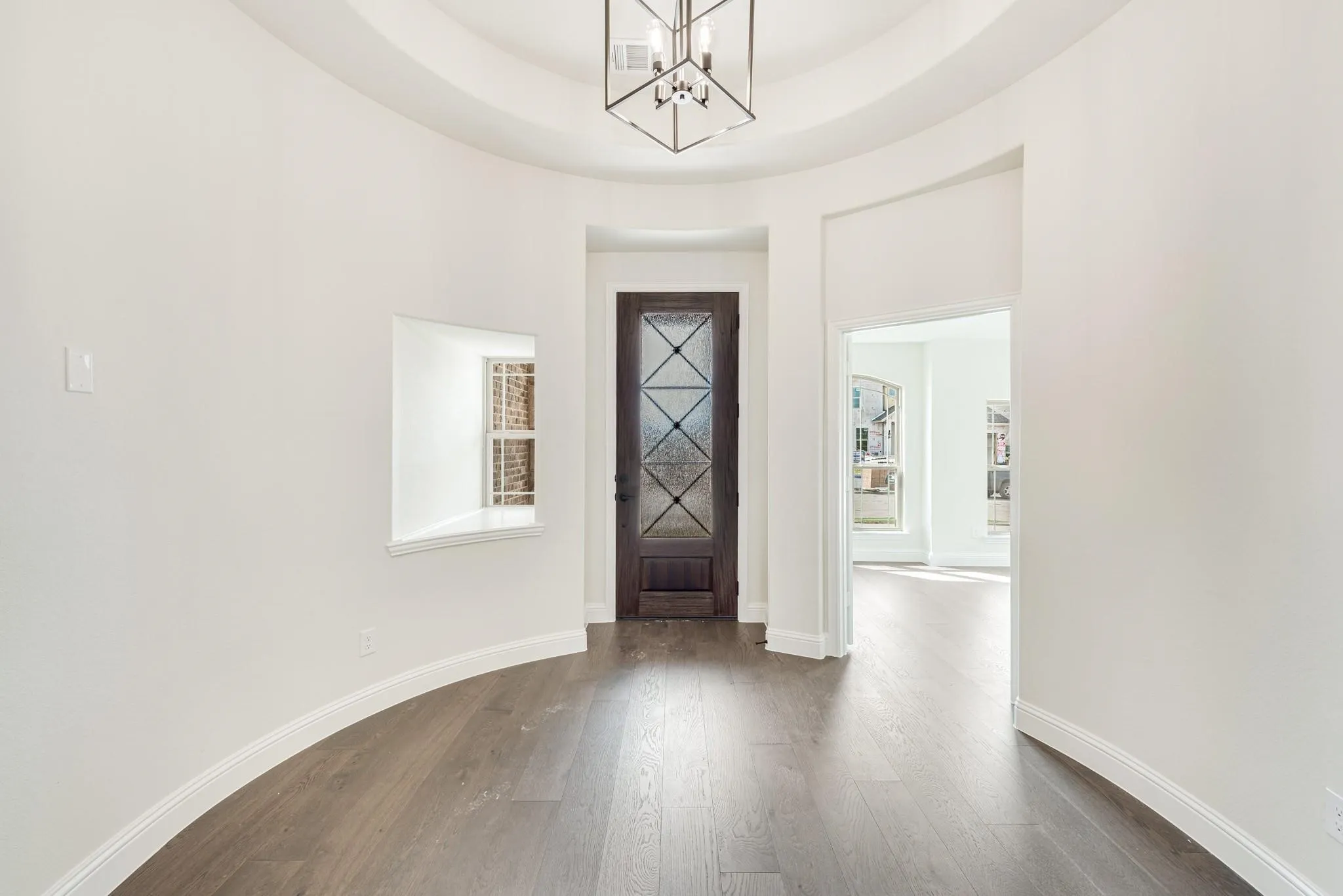 Entryway featuring dark wood-style flooring, a chandelier, and a raised ceiling