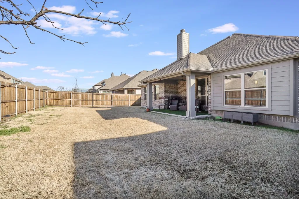 Rear view of house with a patio area, a chimney, a fenced backyard, and roof with shingles