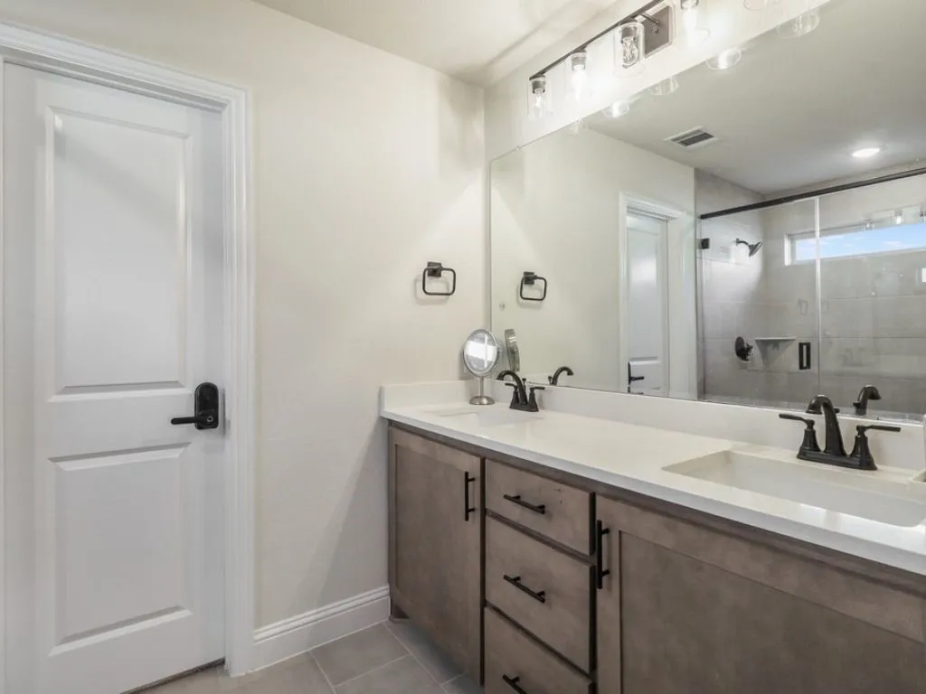 Bathroom with double vanity, a stall shower, and light tile patterned floors