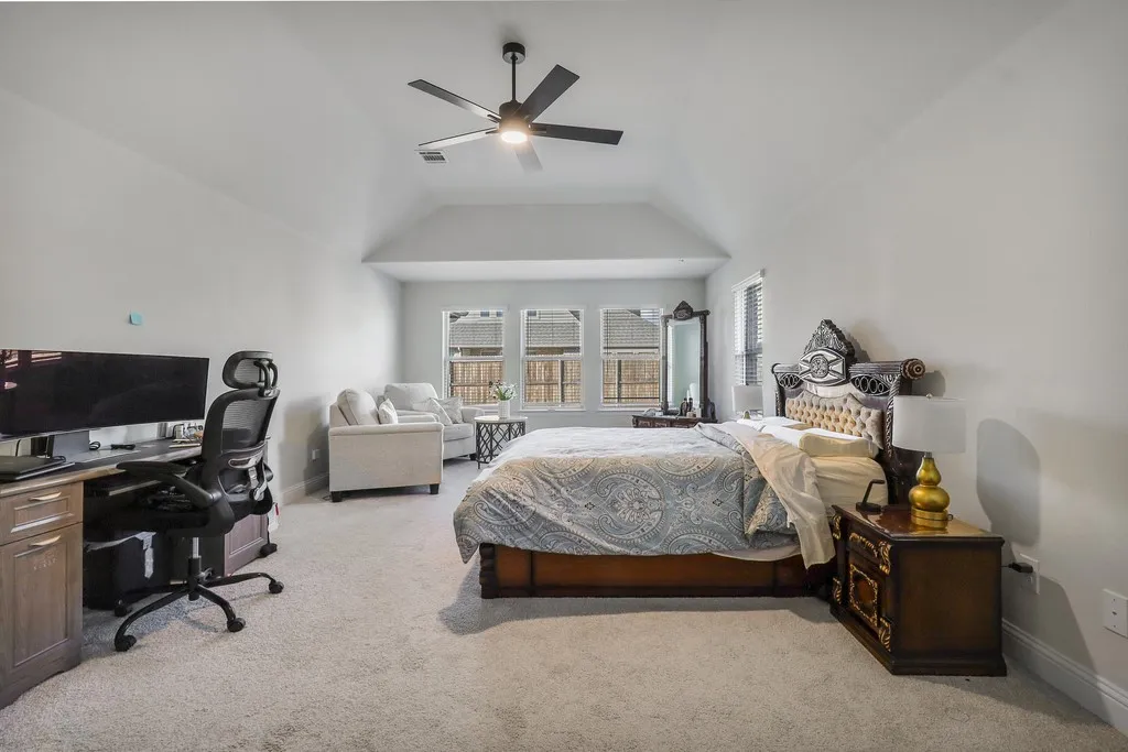 Bedroom featuring an office area, light carpet, ceiling fan, and vaulted ceiling