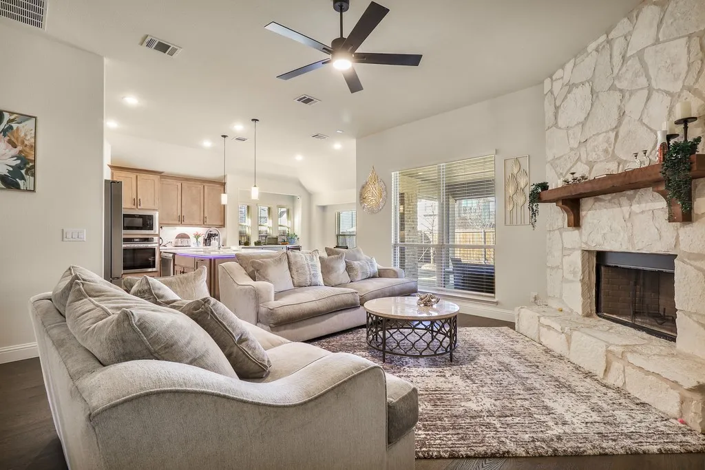 Living room with ceiling fan, dark wood-style flooring, a fireplace, and vaulted ceiling