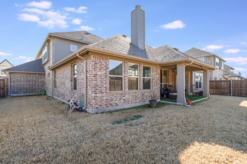 Rear view of property with a fenced backyard, a patio, brick siding, and a chimney